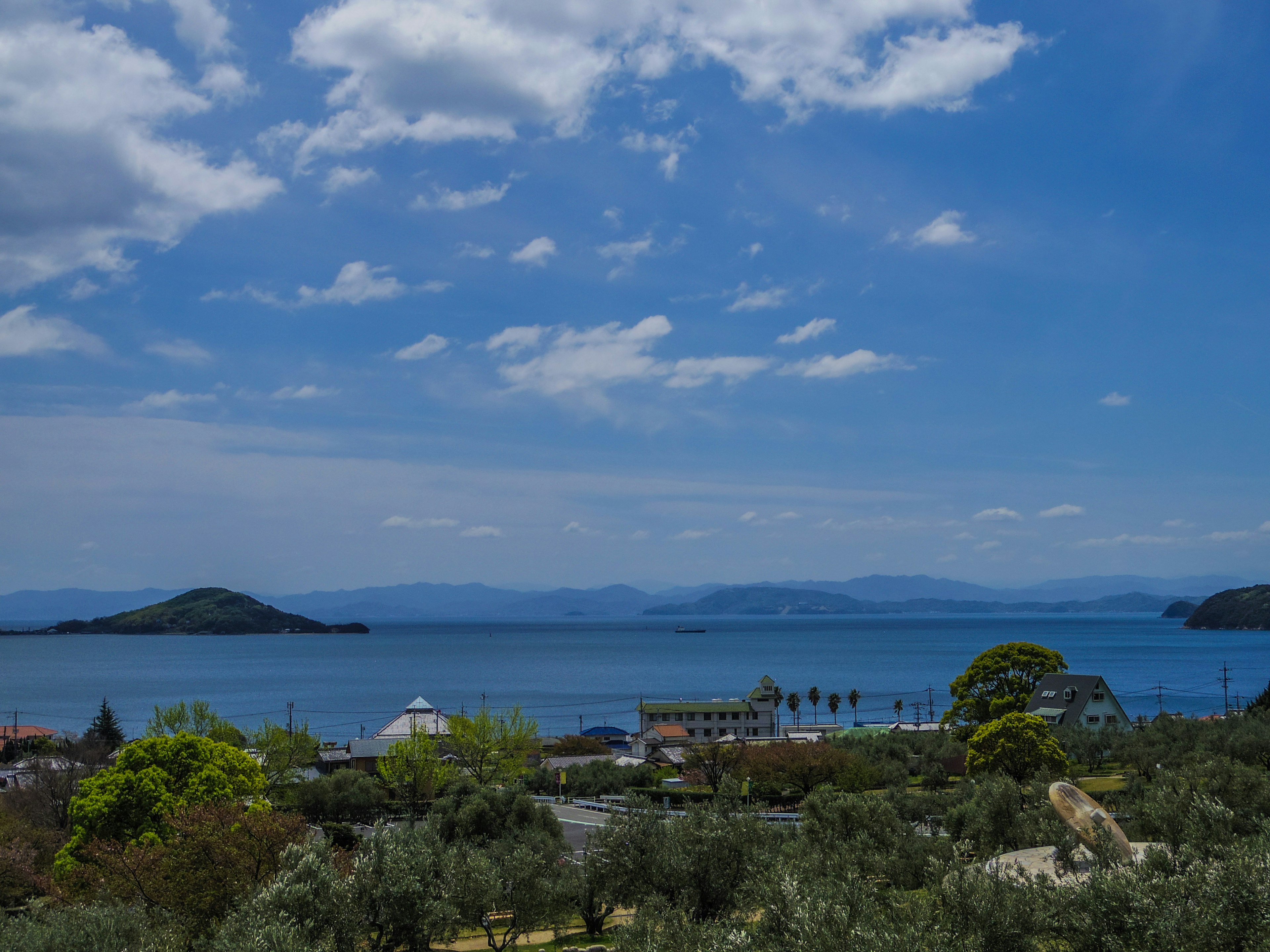 Vista panoramica del mare blu con isole lontane e ulivi rigogliosi