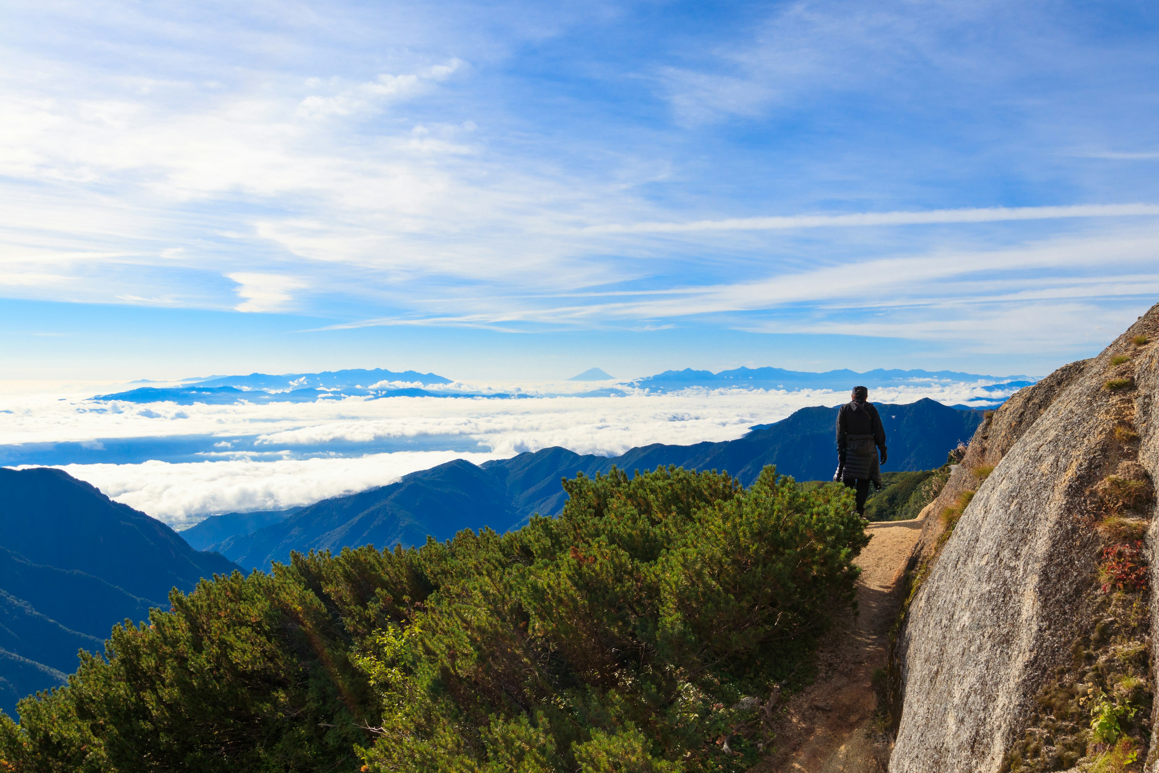 Persona che osserva un paesaggio mozzafiato con nuvole da una cima di montagna