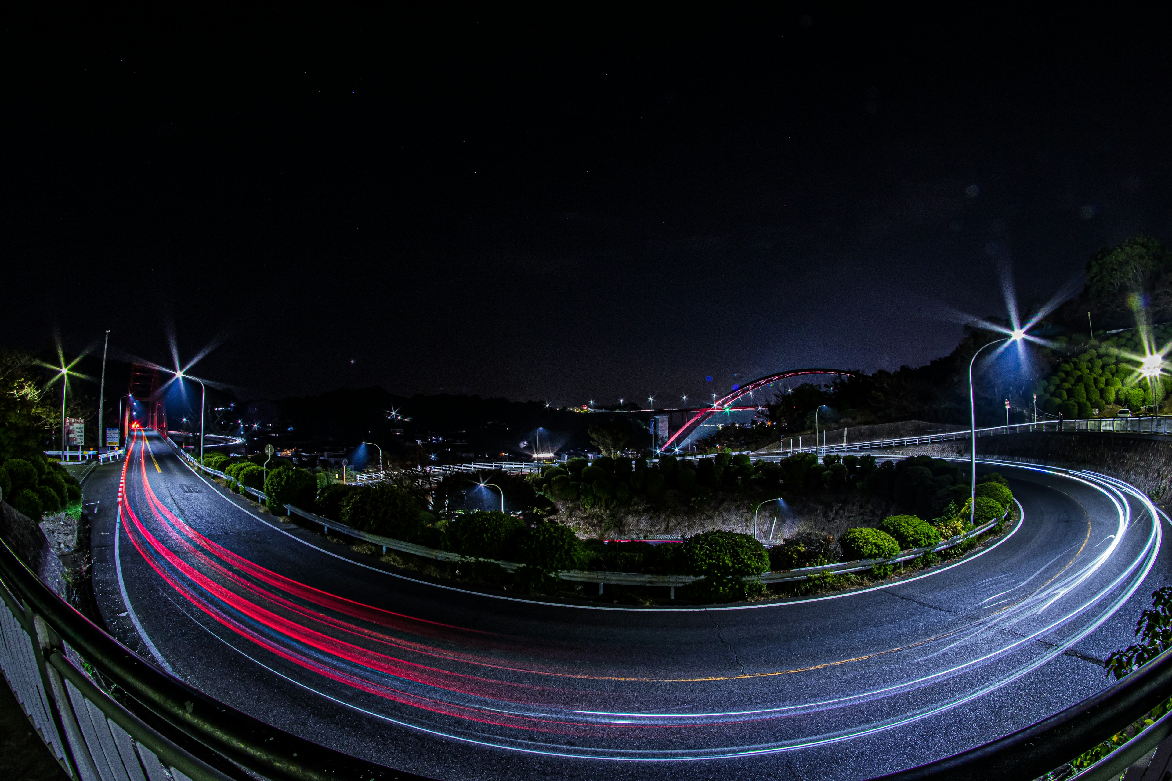 Night view of a winding road with car light trails