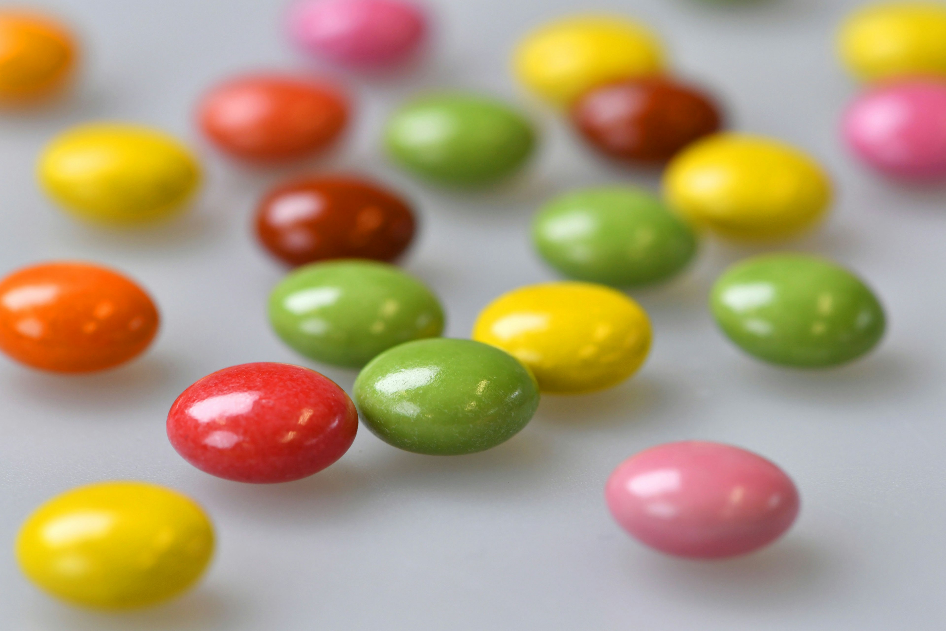 Des bonbons en chocolat colorés éparpillés sur un fond blanc