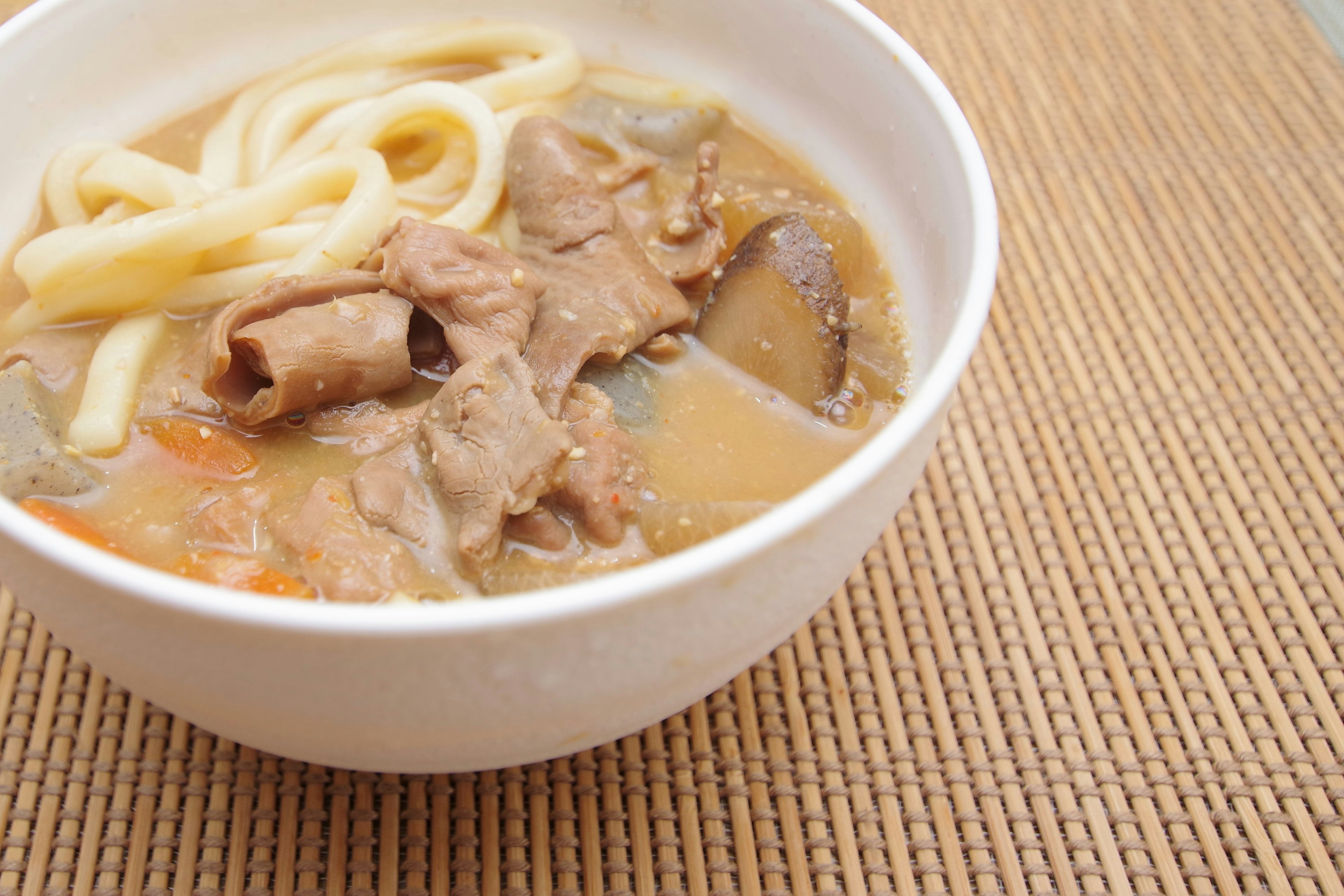 Udon noodles and meat in a white bowl