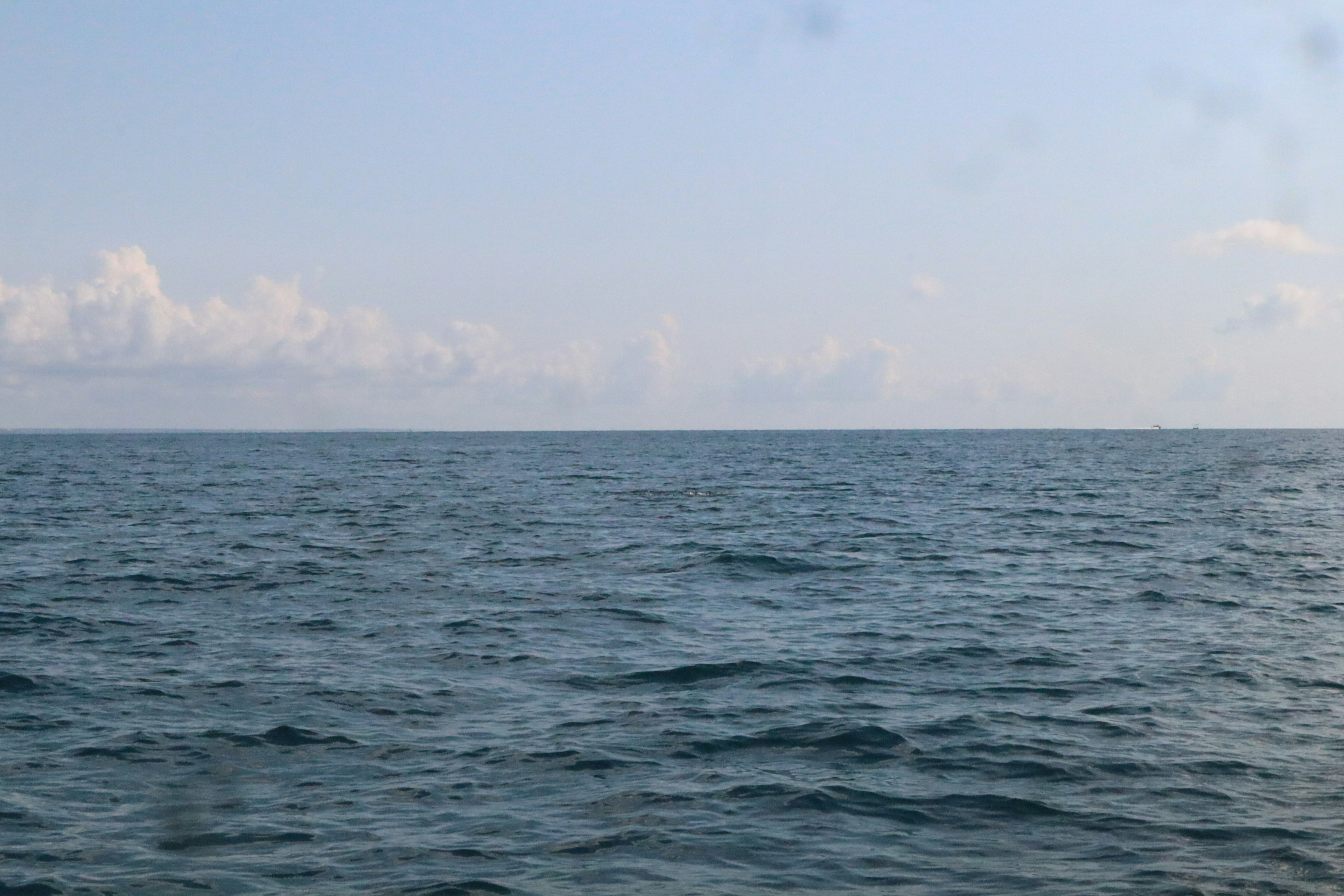 Lanskap laut dan langit biru yang tenang dengan ombak lembut