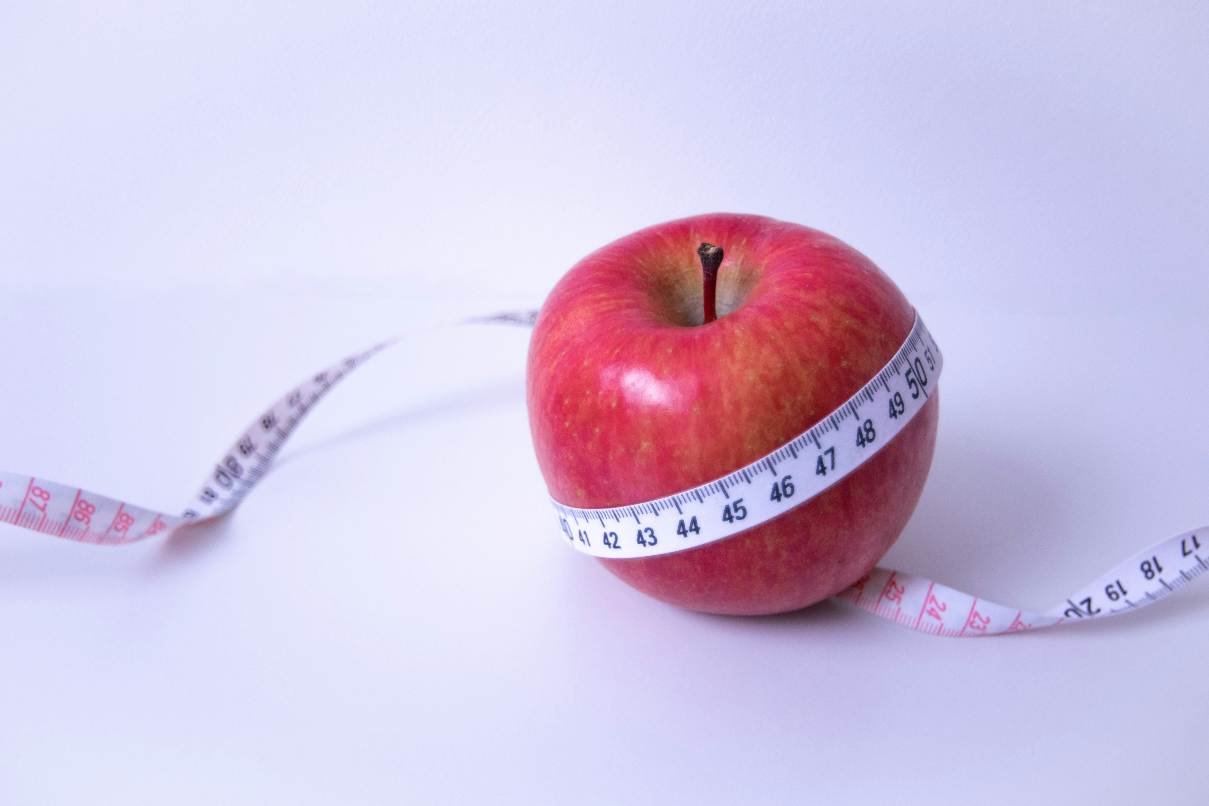 Manzana roja envuelta en una cinta métrica