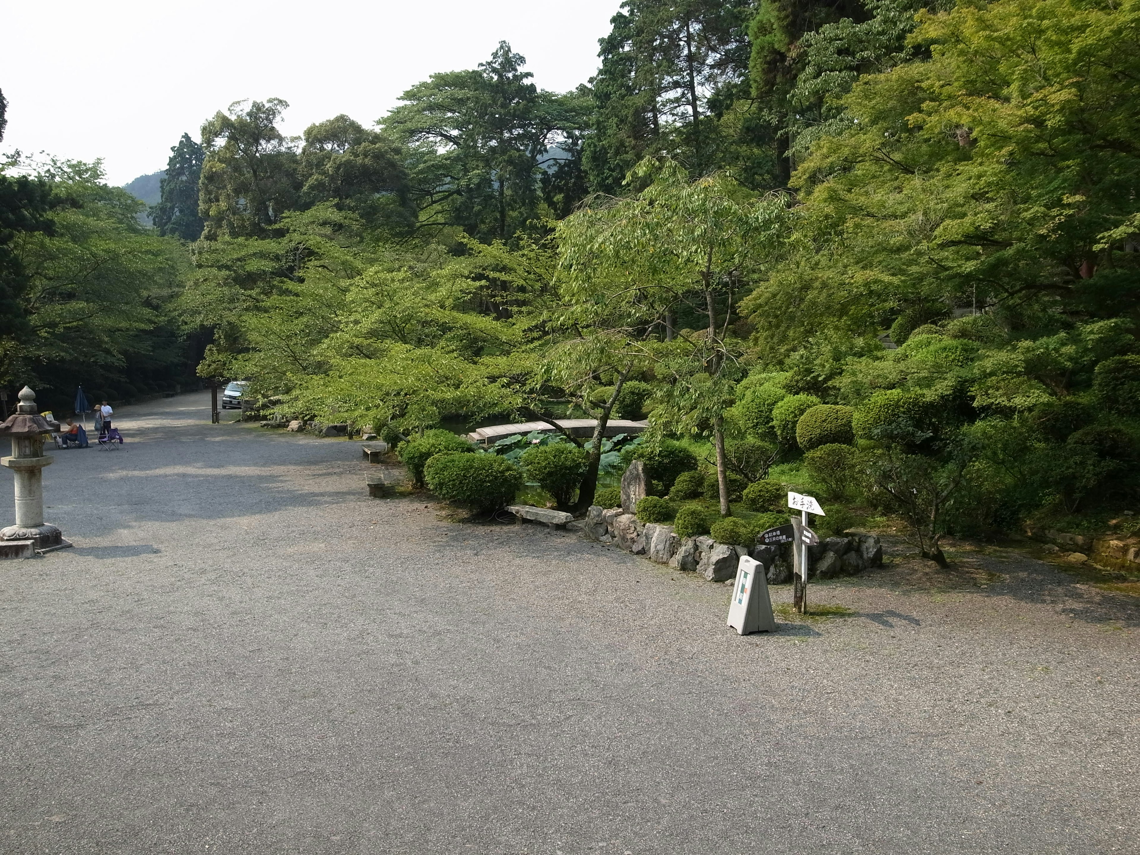 Serene Gartenlandschaft mit grünen Bäumen und gestutzten Sträuchern Steinlaternen und Schilder vorhanden