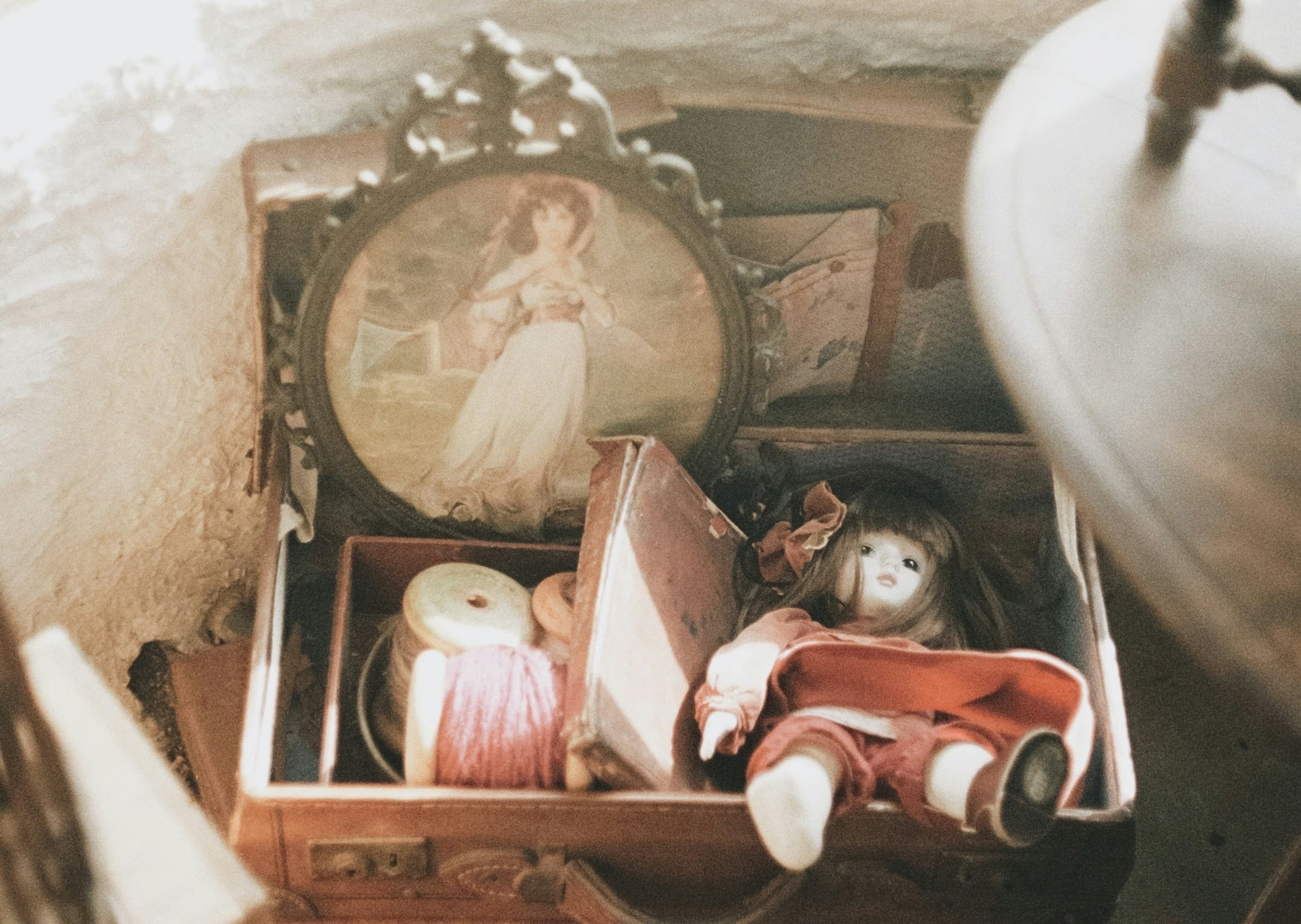 A vintage wooden box containing a doll and spools of thread