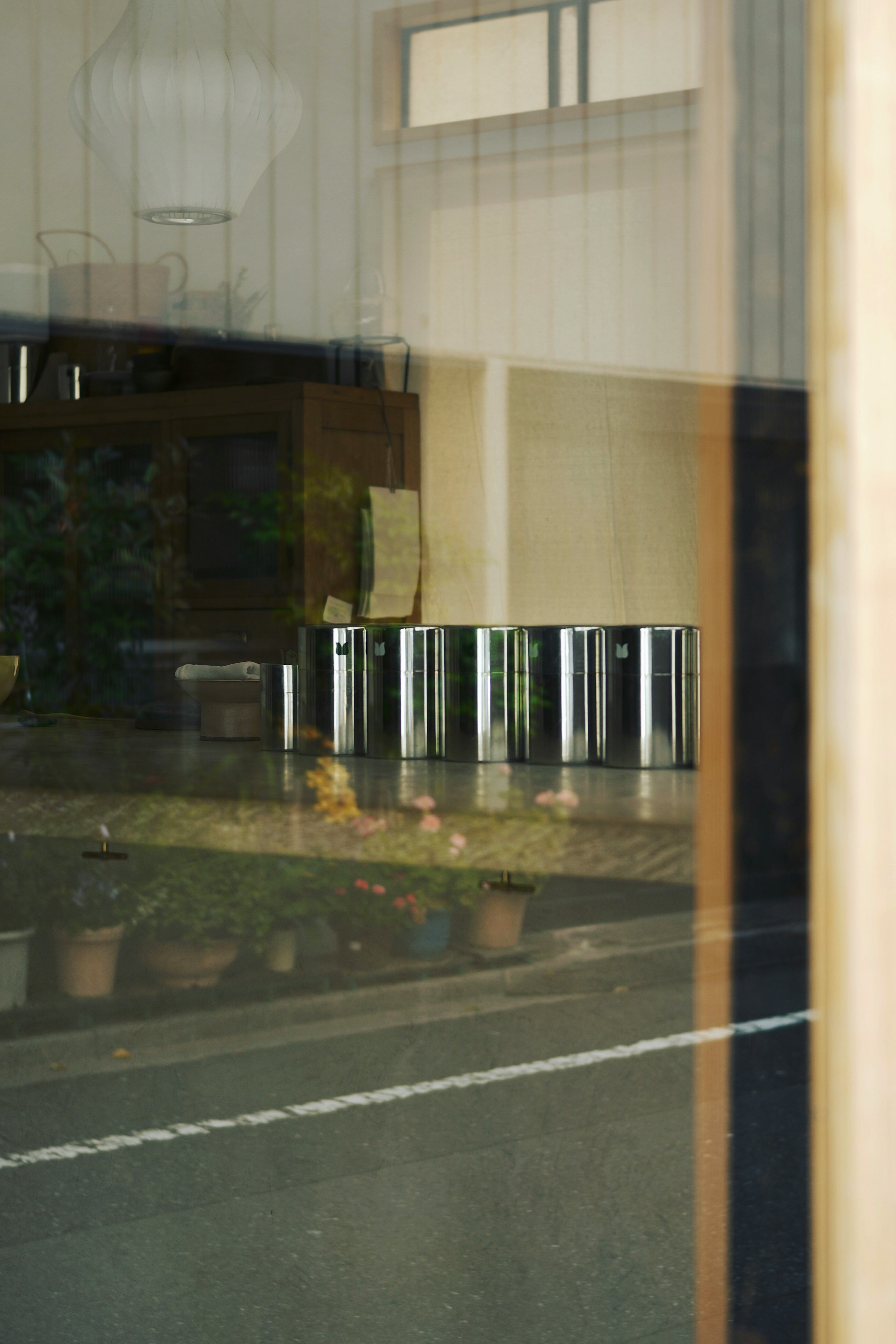 Silver trash bins and potted plants visible through glass