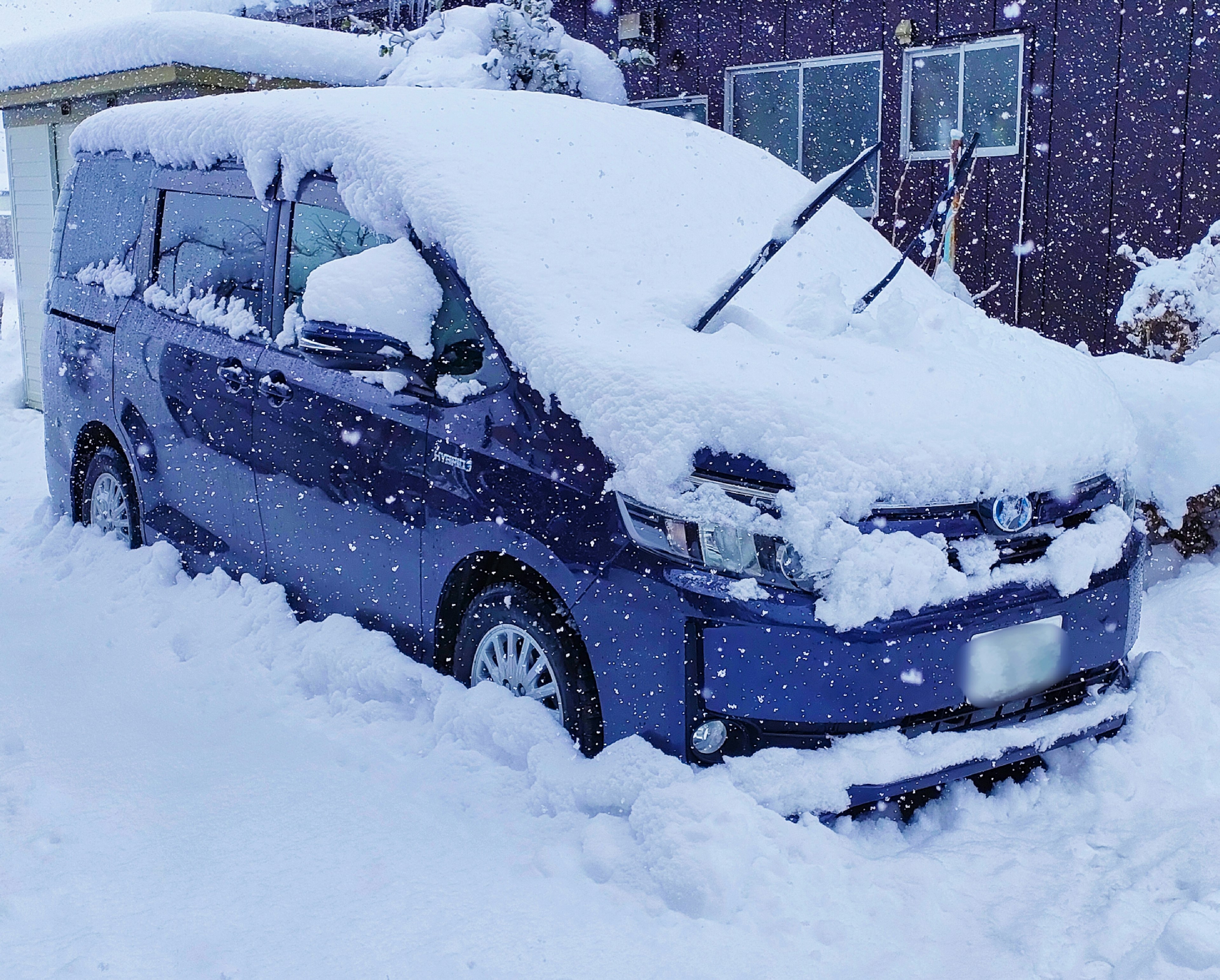 A blue minivan covered in snow