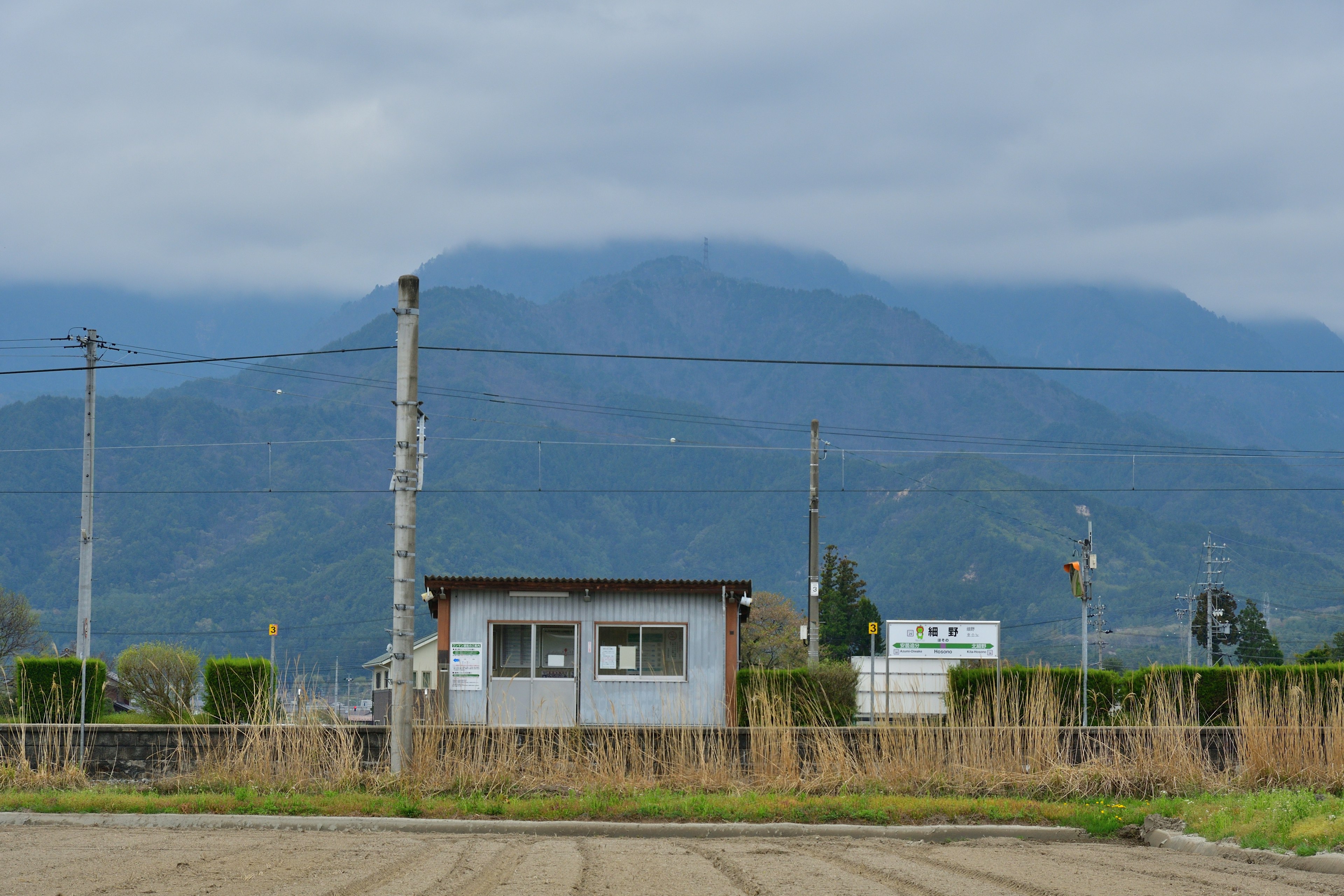 山の背景に小さな建物と電線がある風景