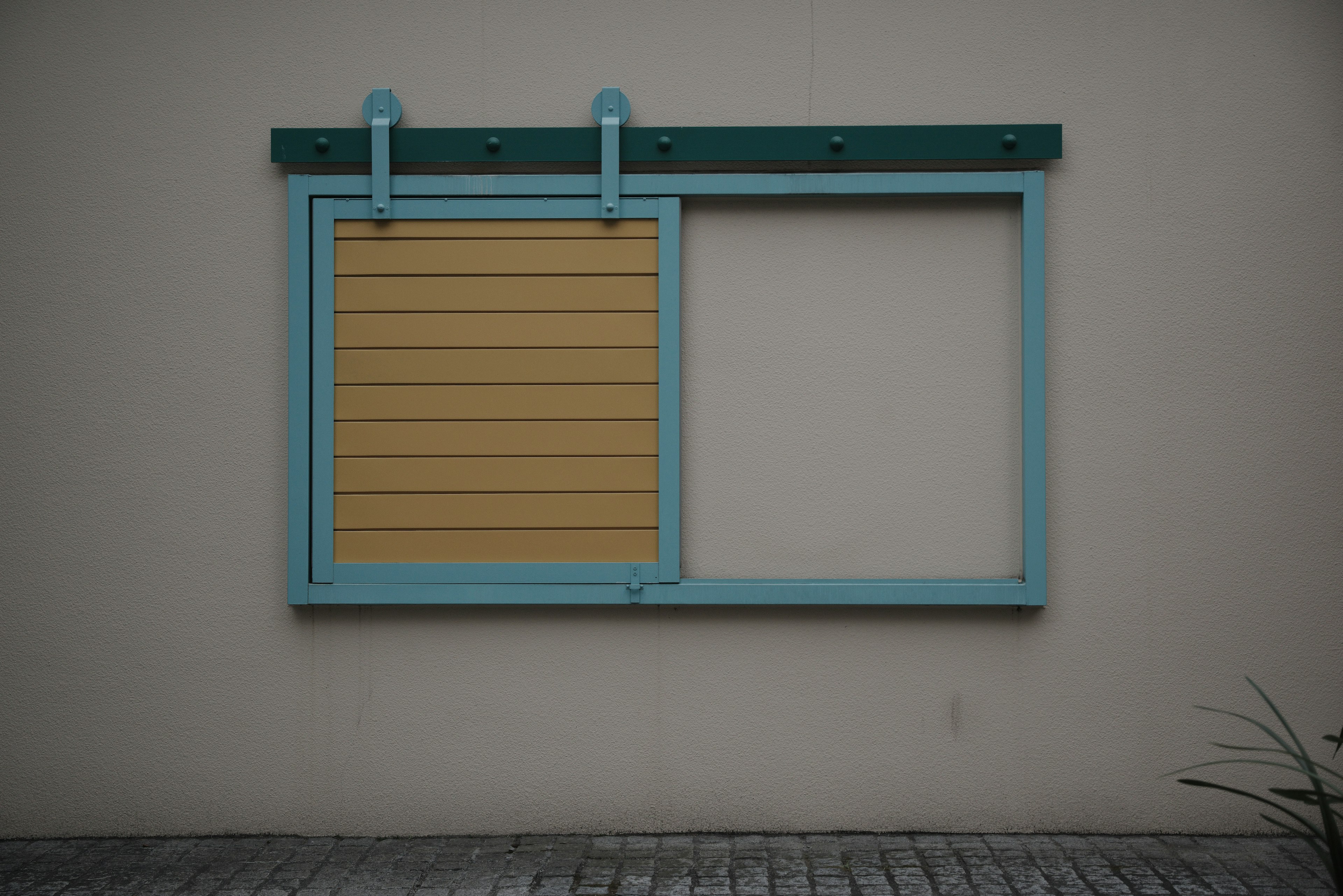 A blue-framed window featuring a yellow slatted section and an empty pane