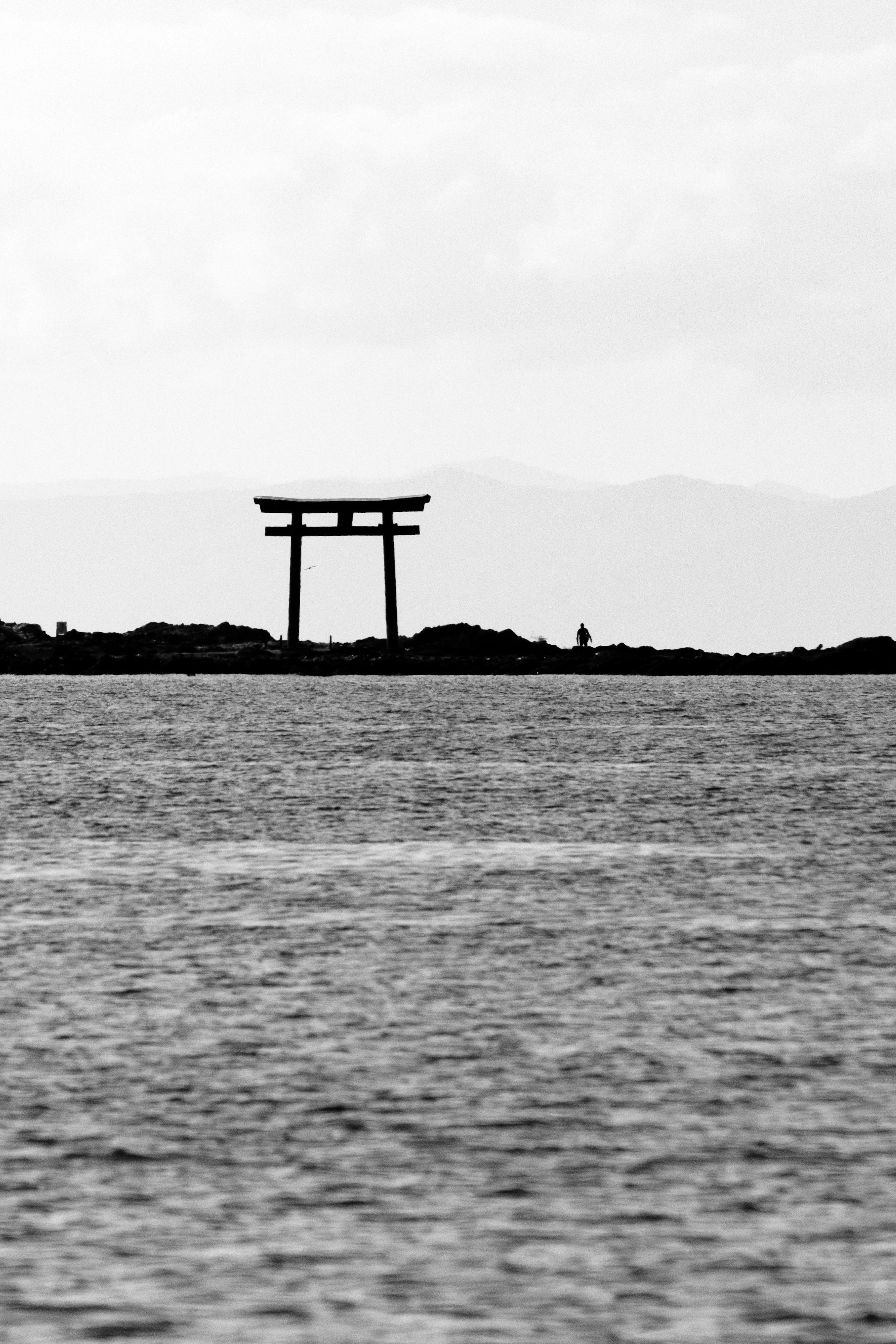 海に浮かぶ鳥居のシルエットと静かな水面