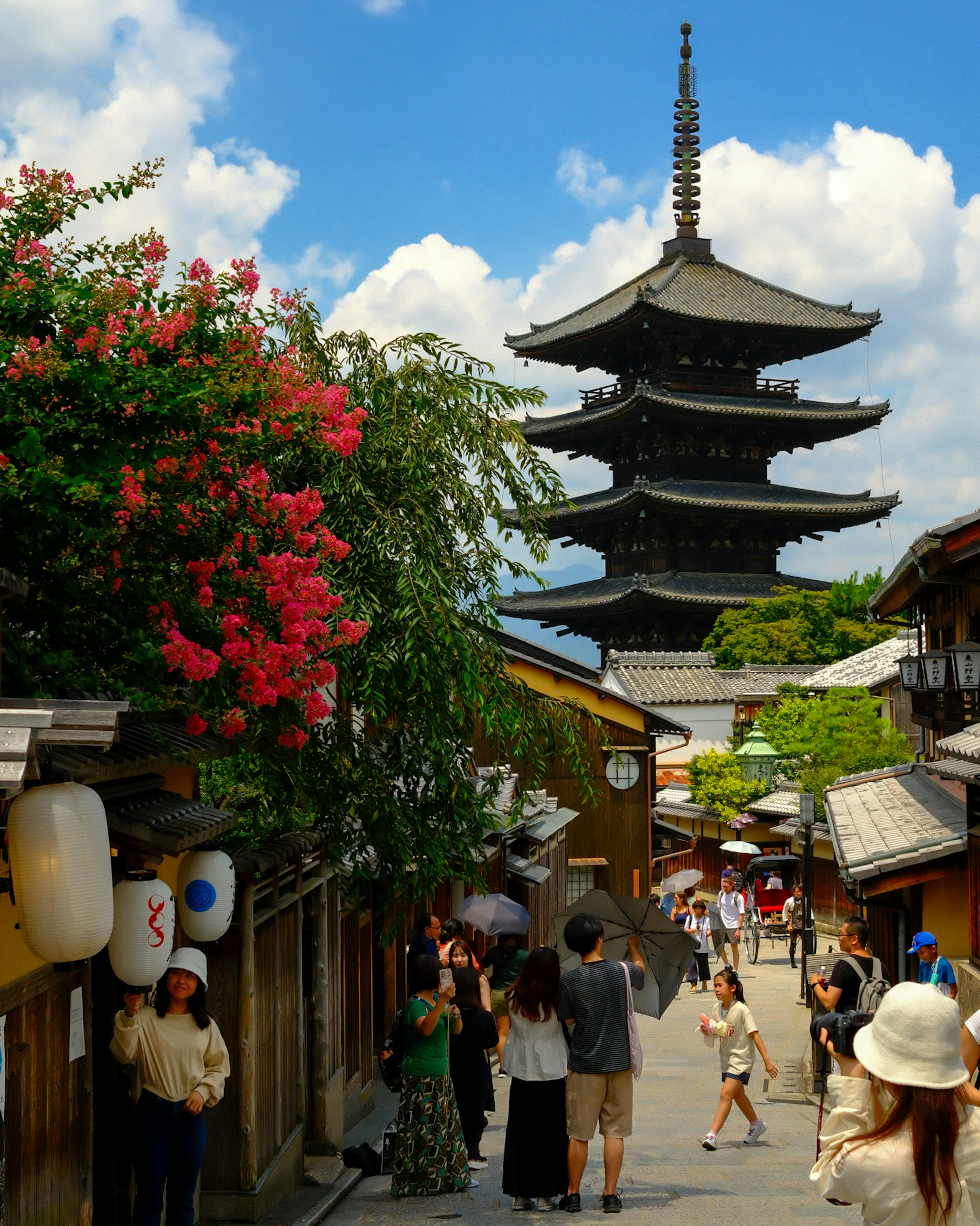 Calle histórica con una pagoda de cinco pisos y flores vibrantes en Kioto