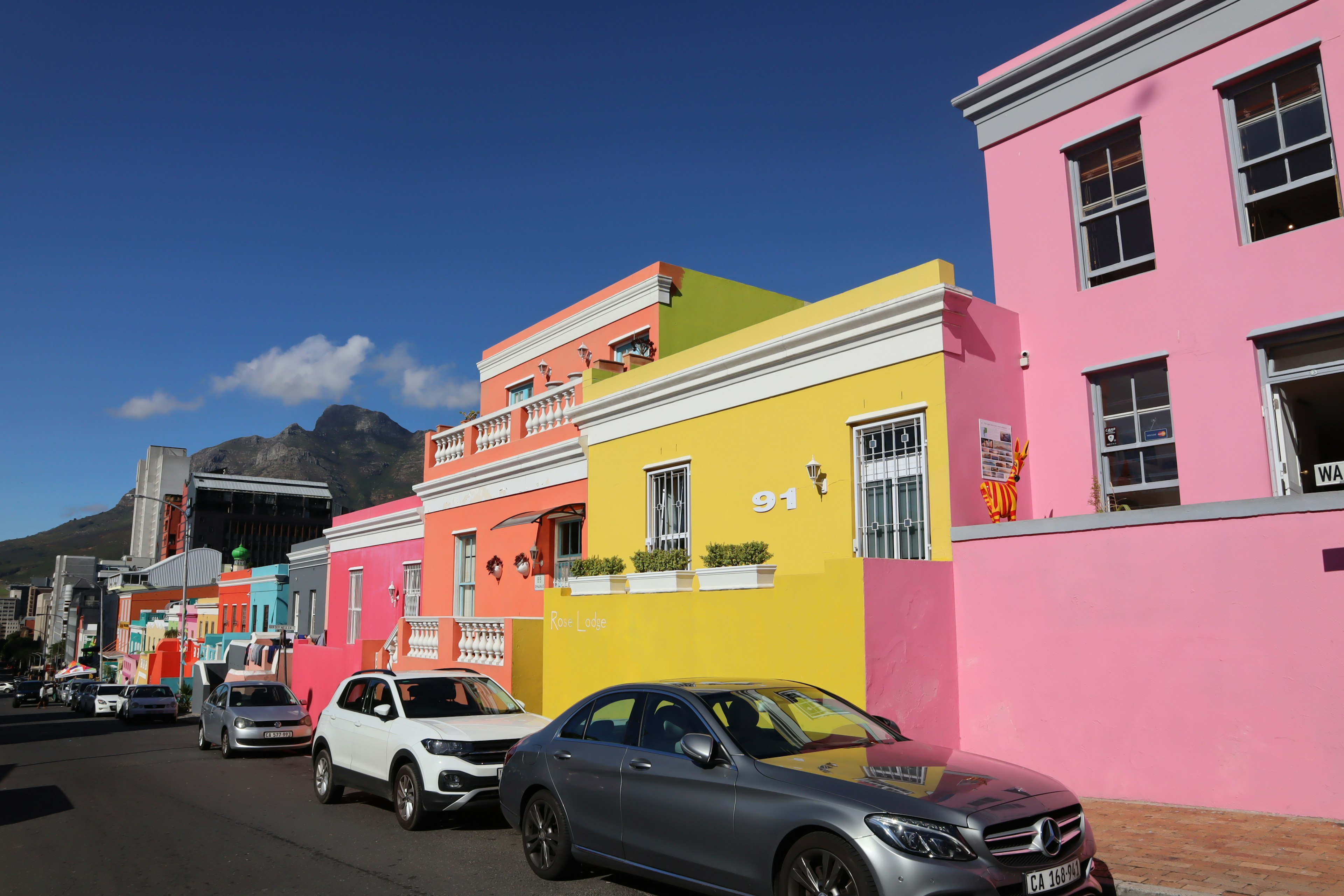 Colorful houses line the street with parked cars