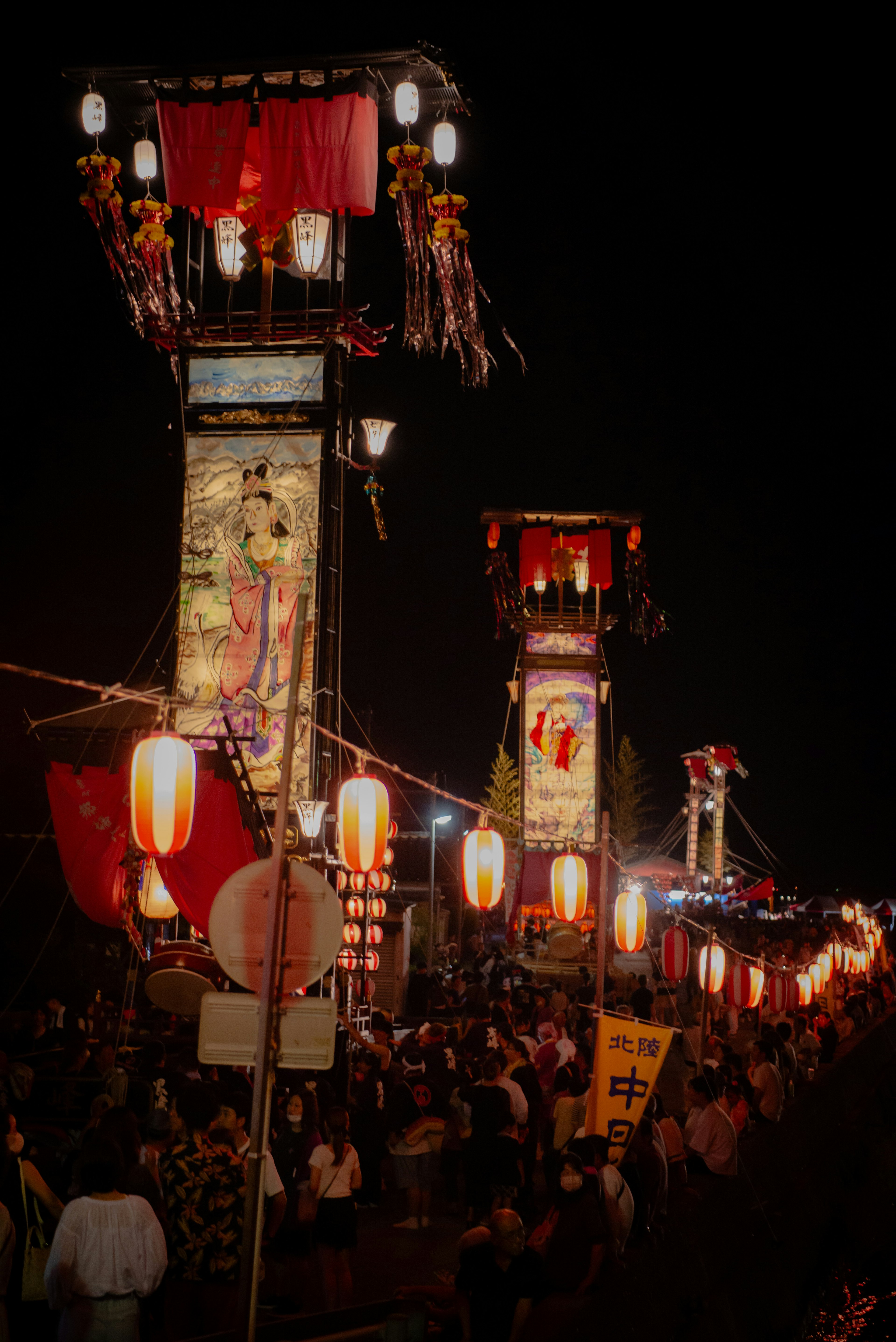 夜の祭りの様子提灯と巨大な山車が並ぶ人々が集まる