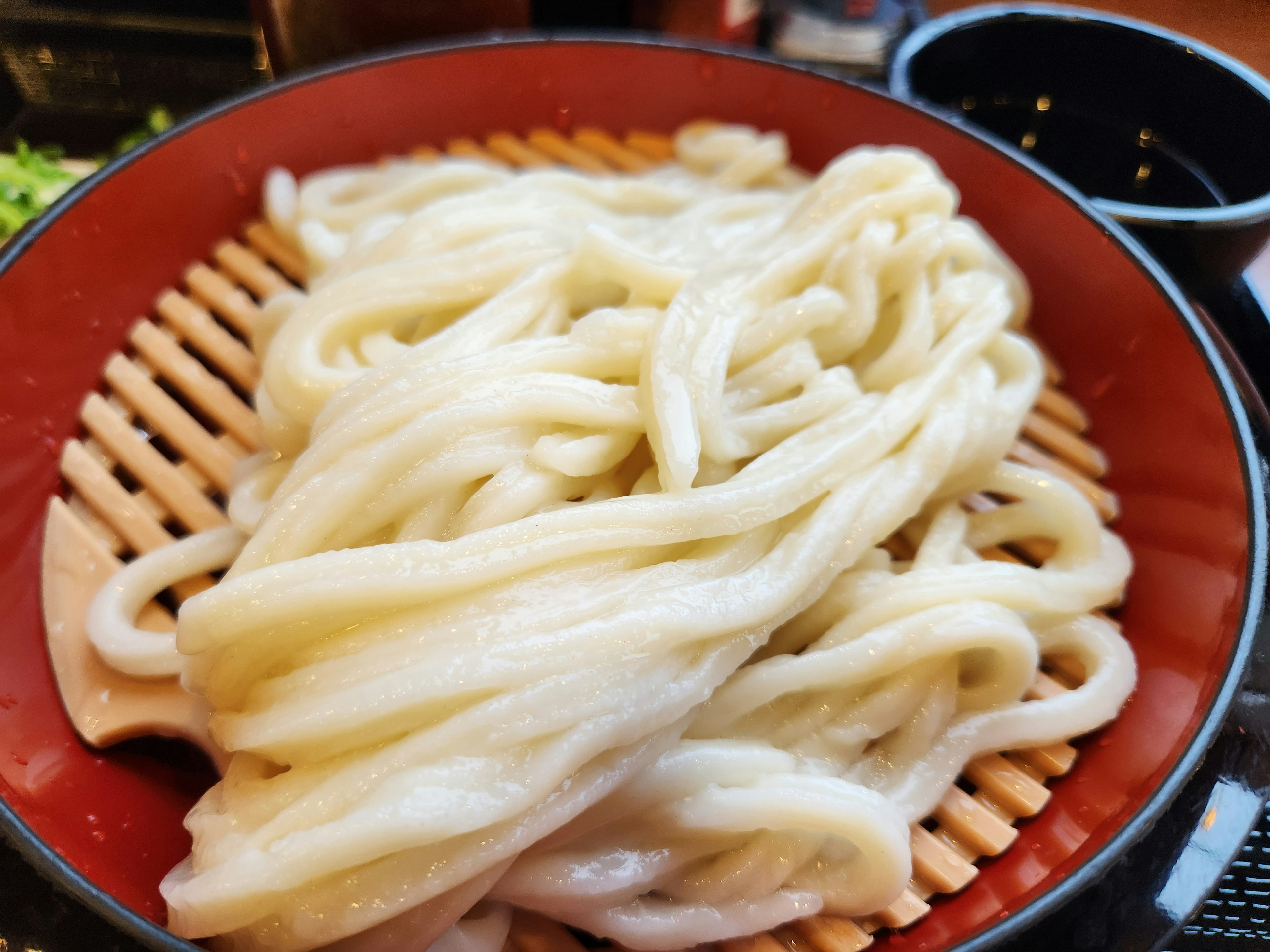 Thick and smooth udon noodles served in a red bowl