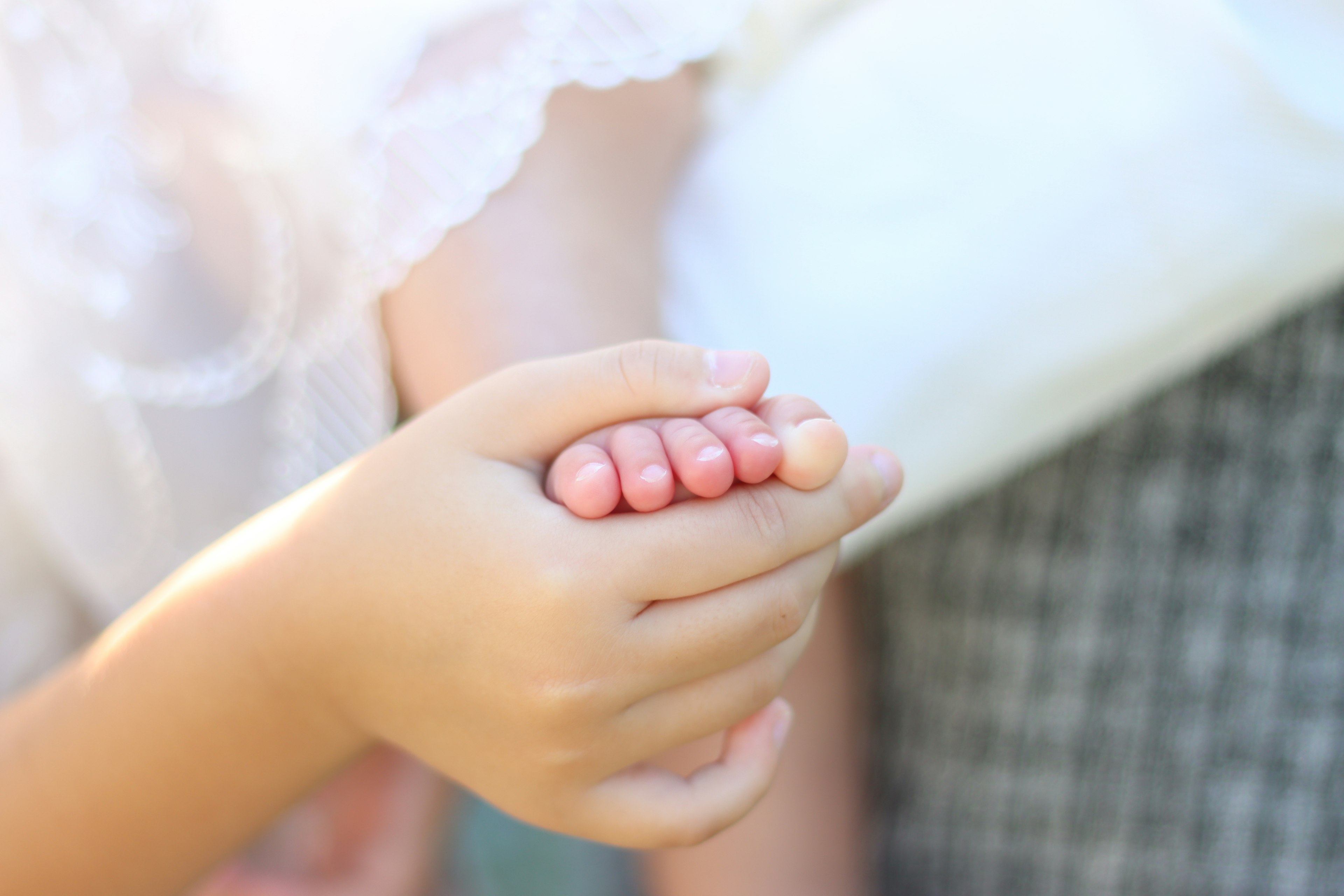 Close-up of hands gently holding a baby's foot