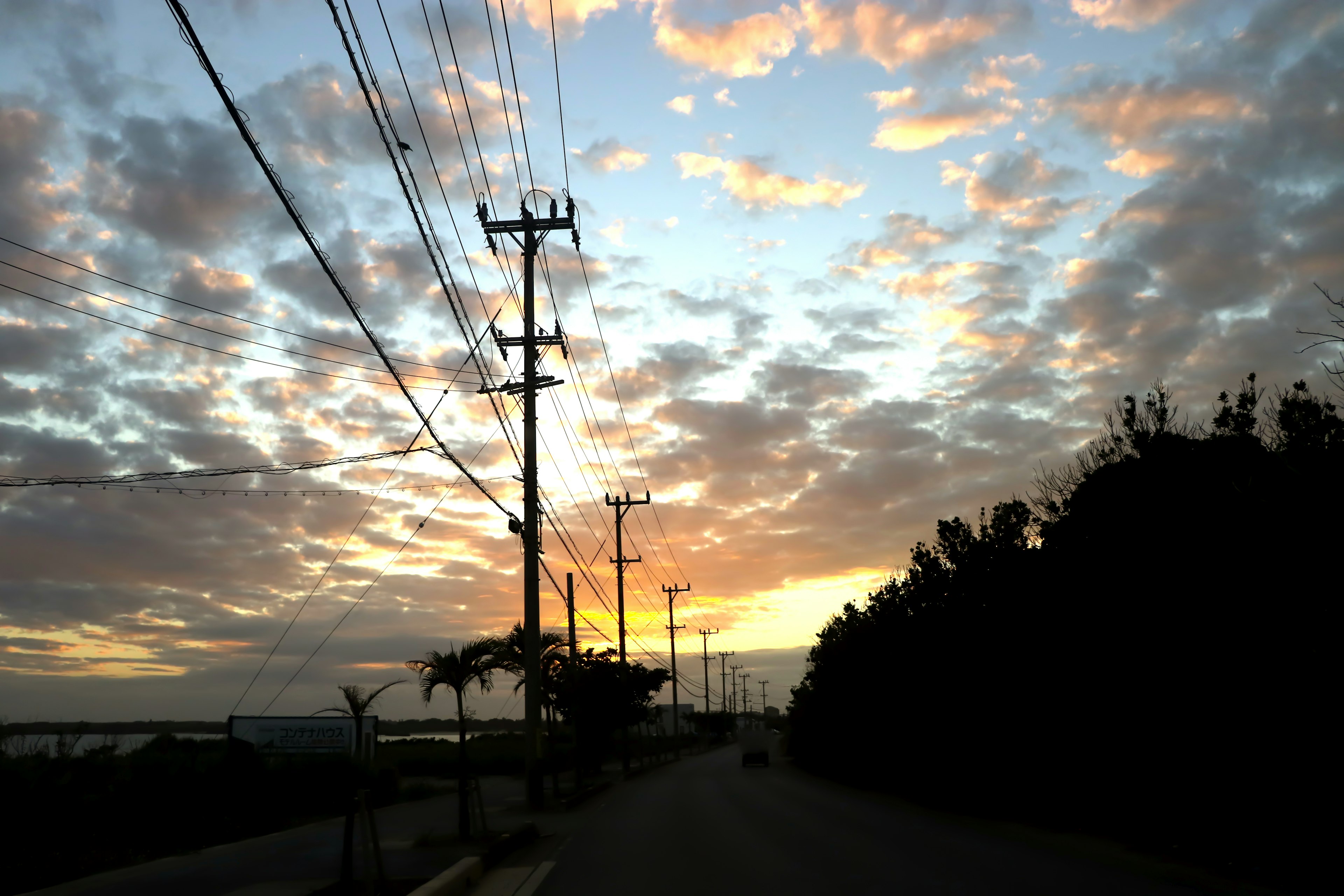 A scenic view of a sunset sky with utility poles along a road