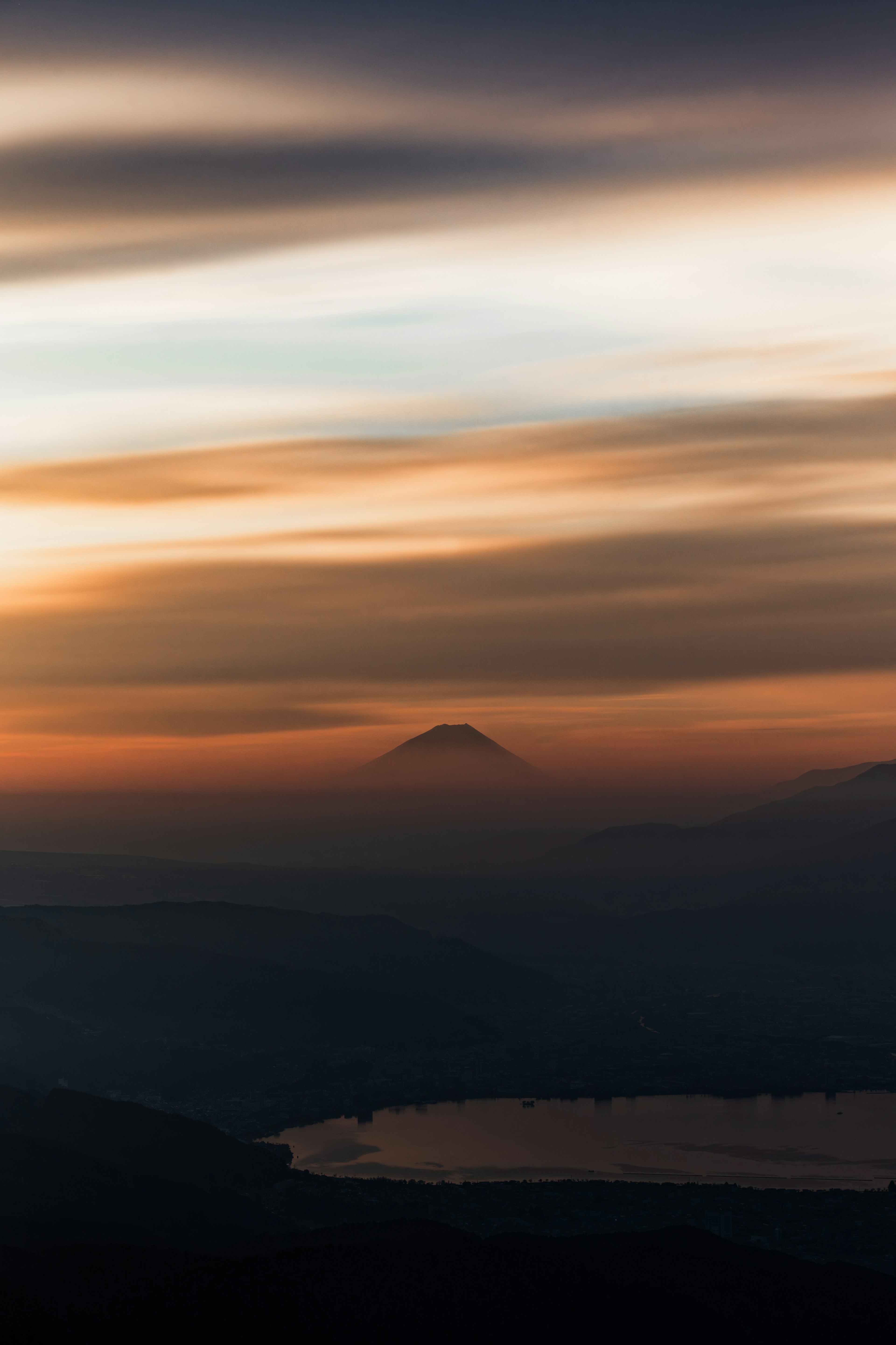 夕焼けの中に浮かぶ富士山のシルエットと湖の景色