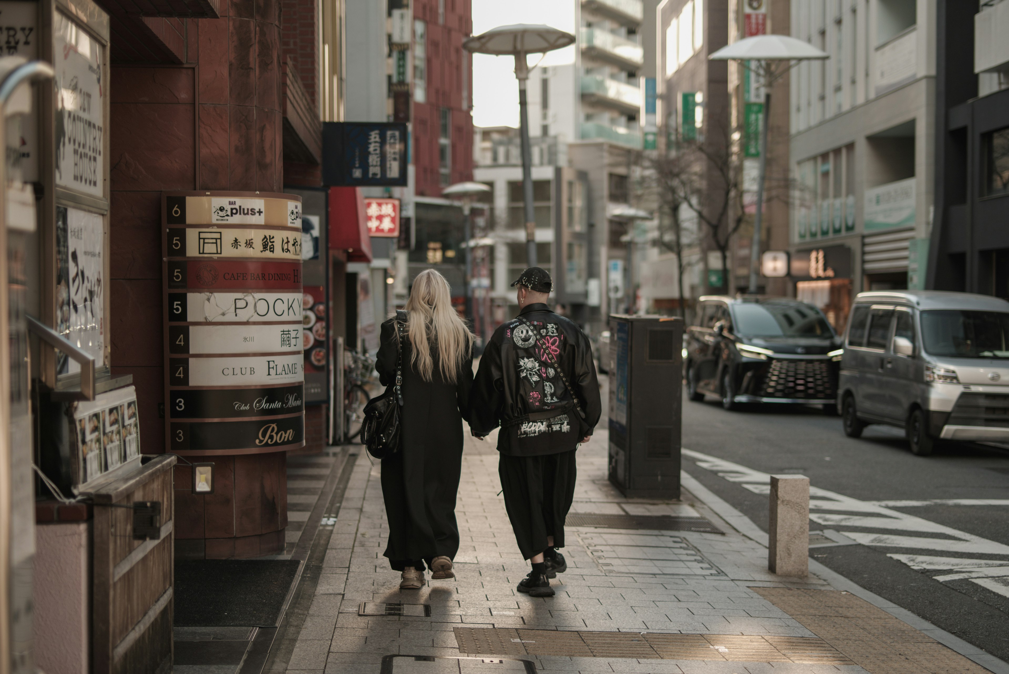 一對情侶走在有商店和車輛的城市街道上