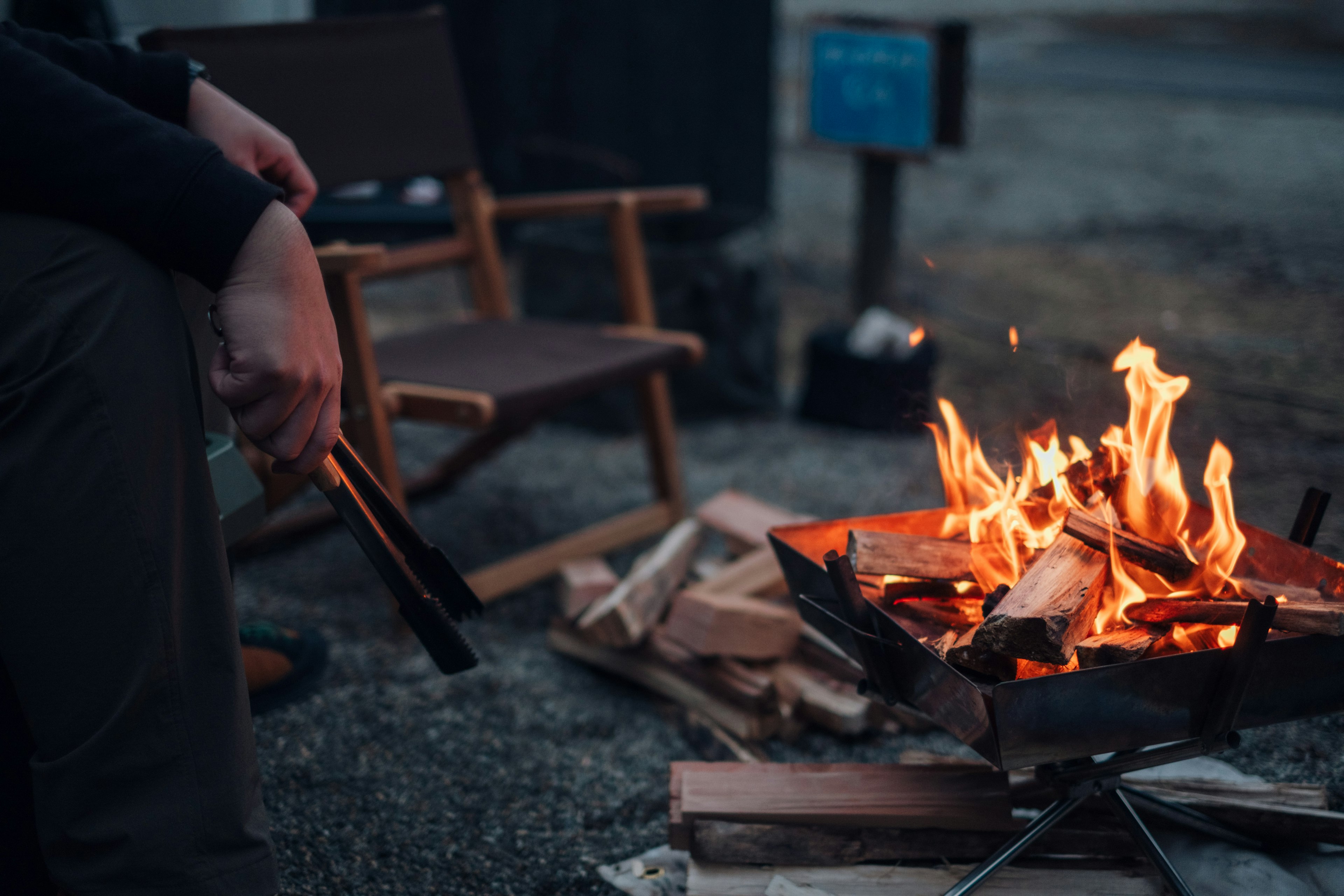 Eine Person entspannt sich am Lagerfeuer mit einem Klappstuhl in der Nähe