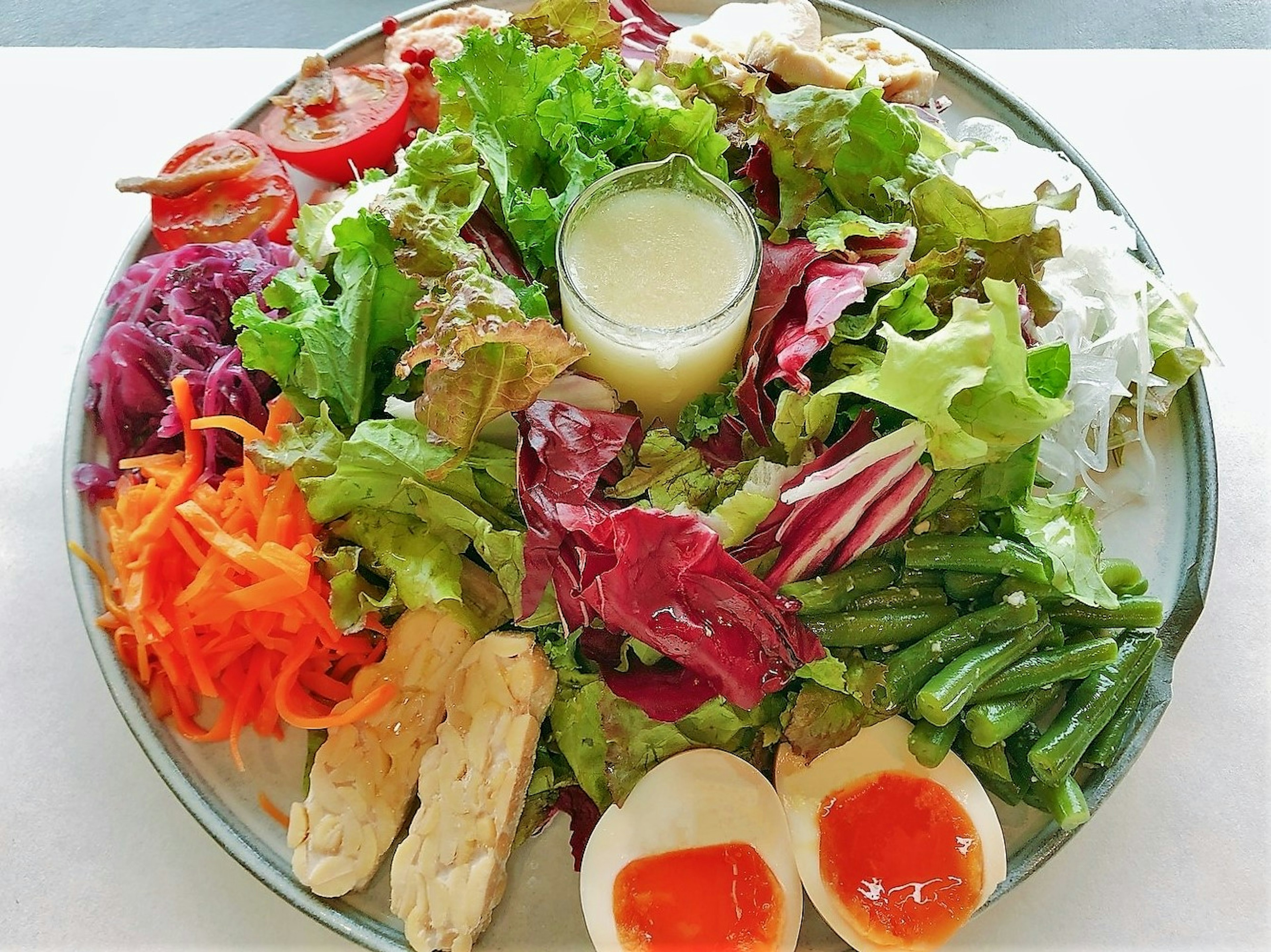 Une assiette de salade colorée avec des légumes frais, des morceaux de poulet et des œufs durs