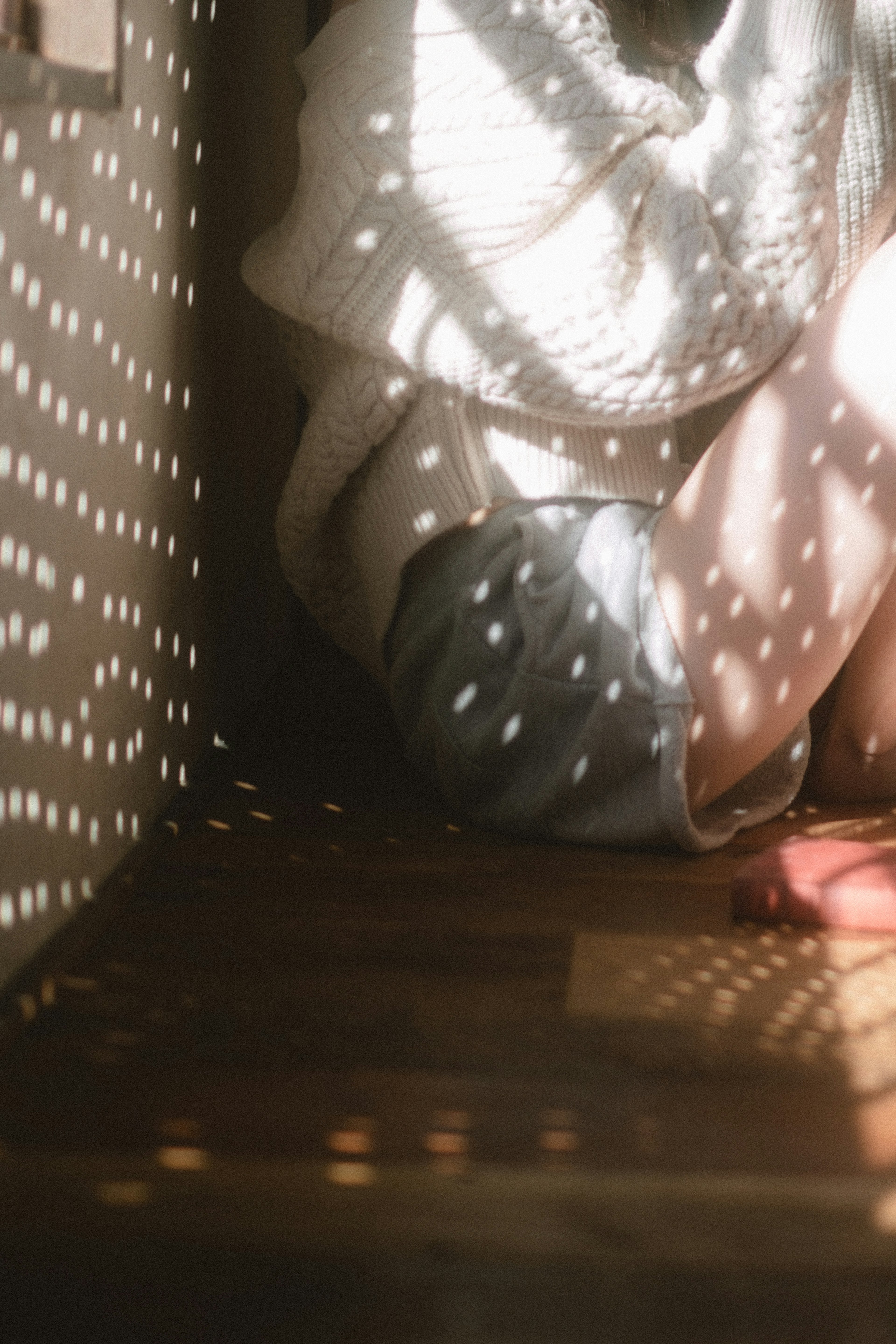 Une personne assise dans un coin d'une pièce avec une lumière douce créant des ombres