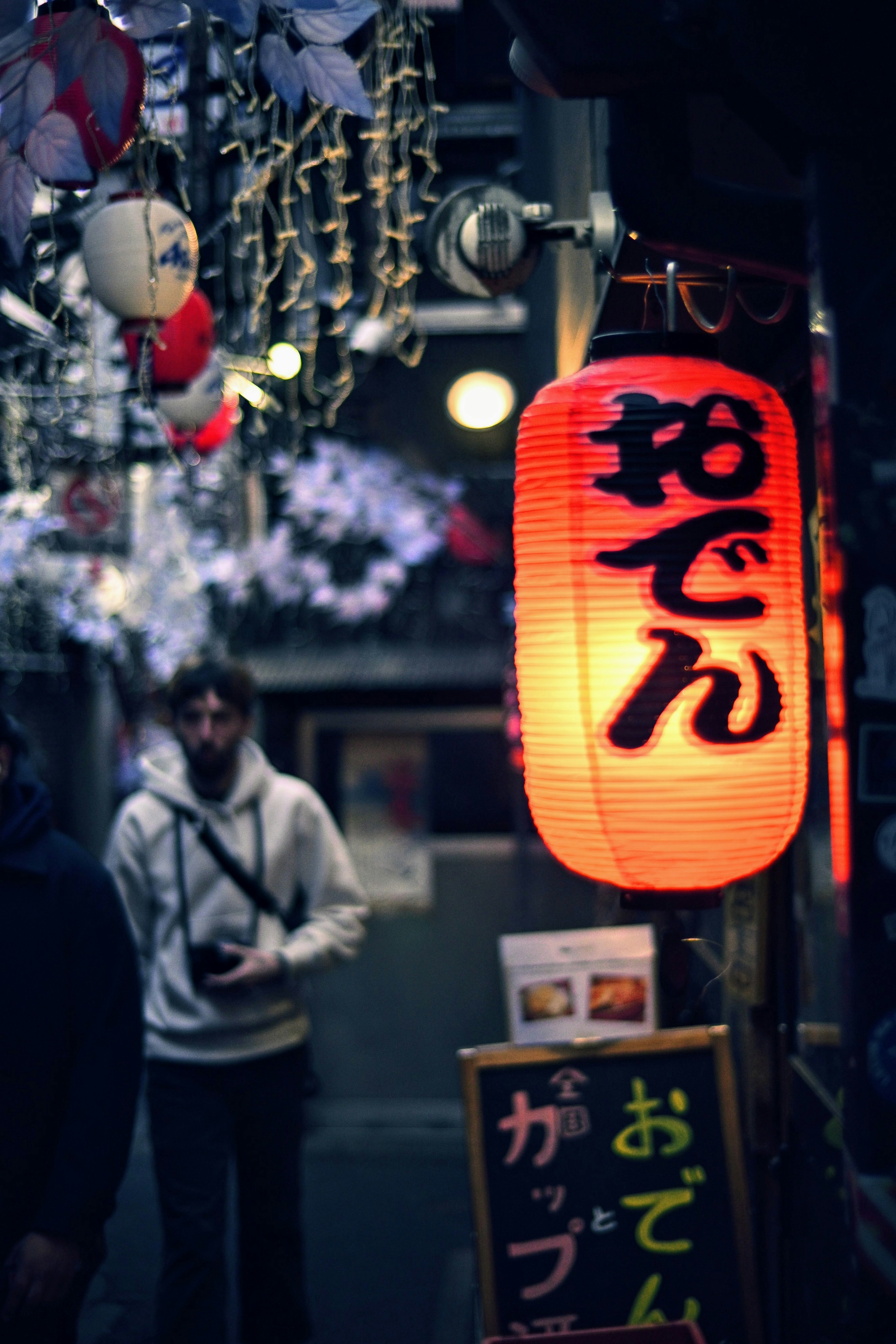 夜间街道上的明亮红灯笼，招牌上写着おでん