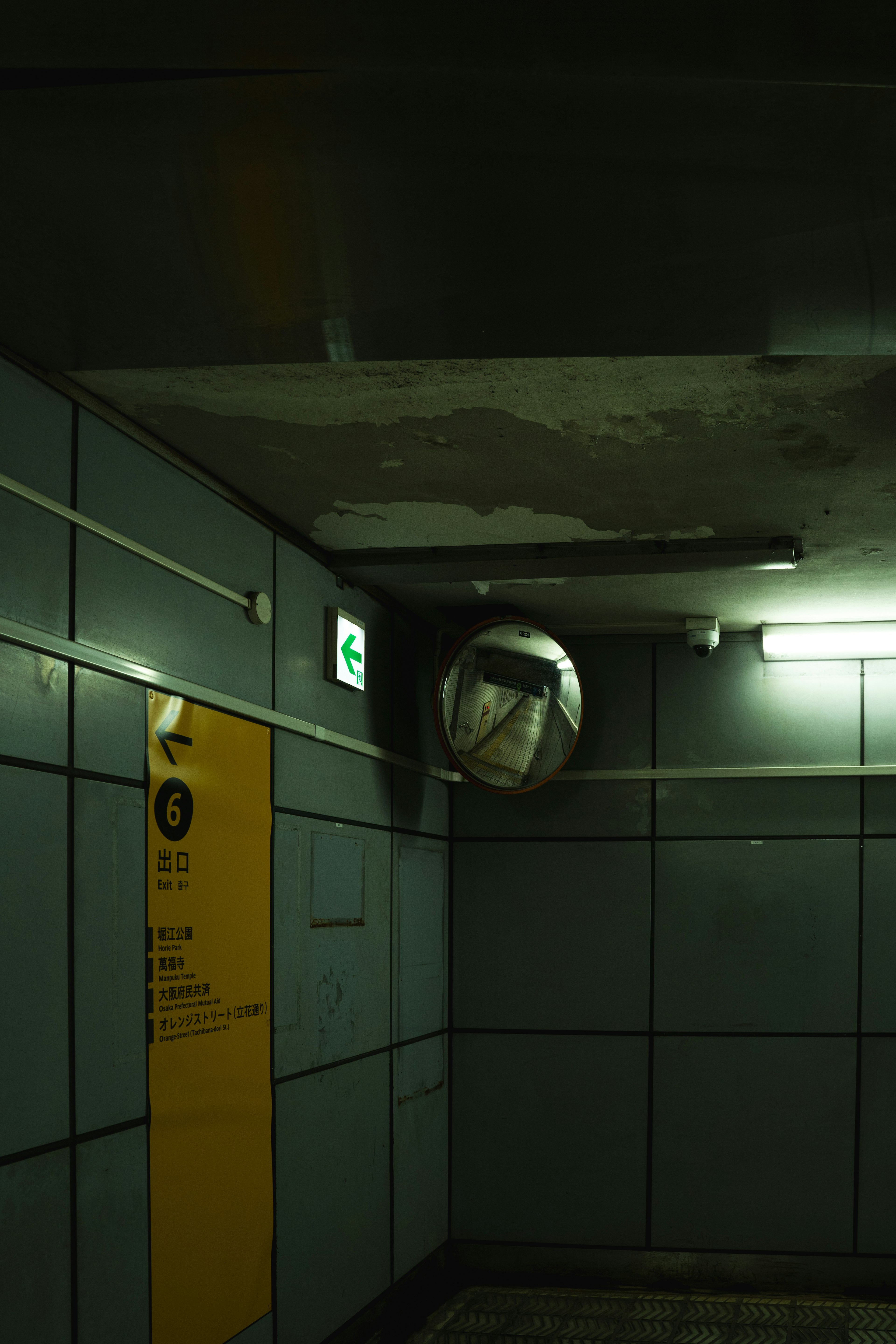 Tunnel della metropolitana poco illuminato con una ventola rotonda e un segnale informativo giallo