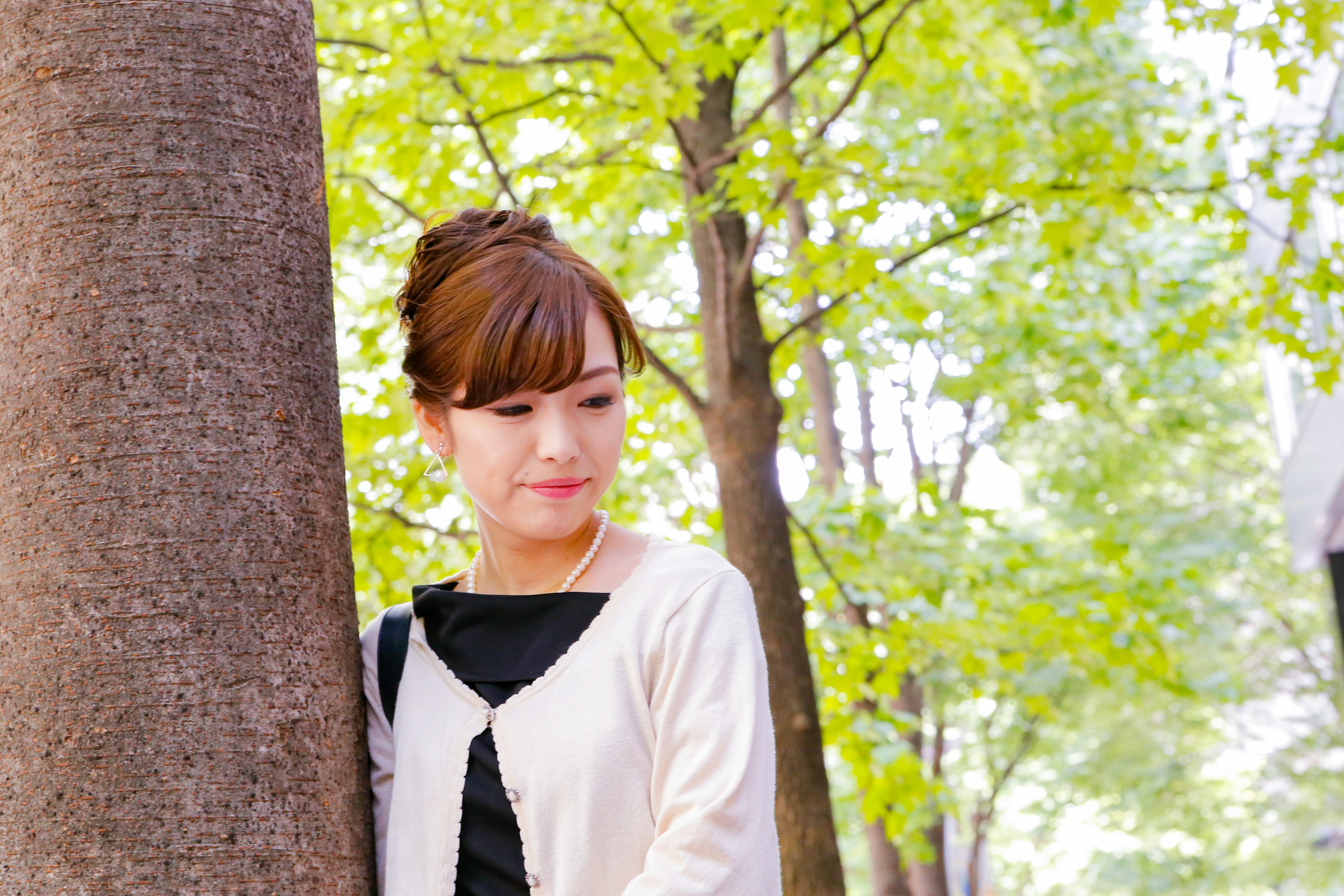 Portrait of a woman standing by a tree surrounded by green leaves