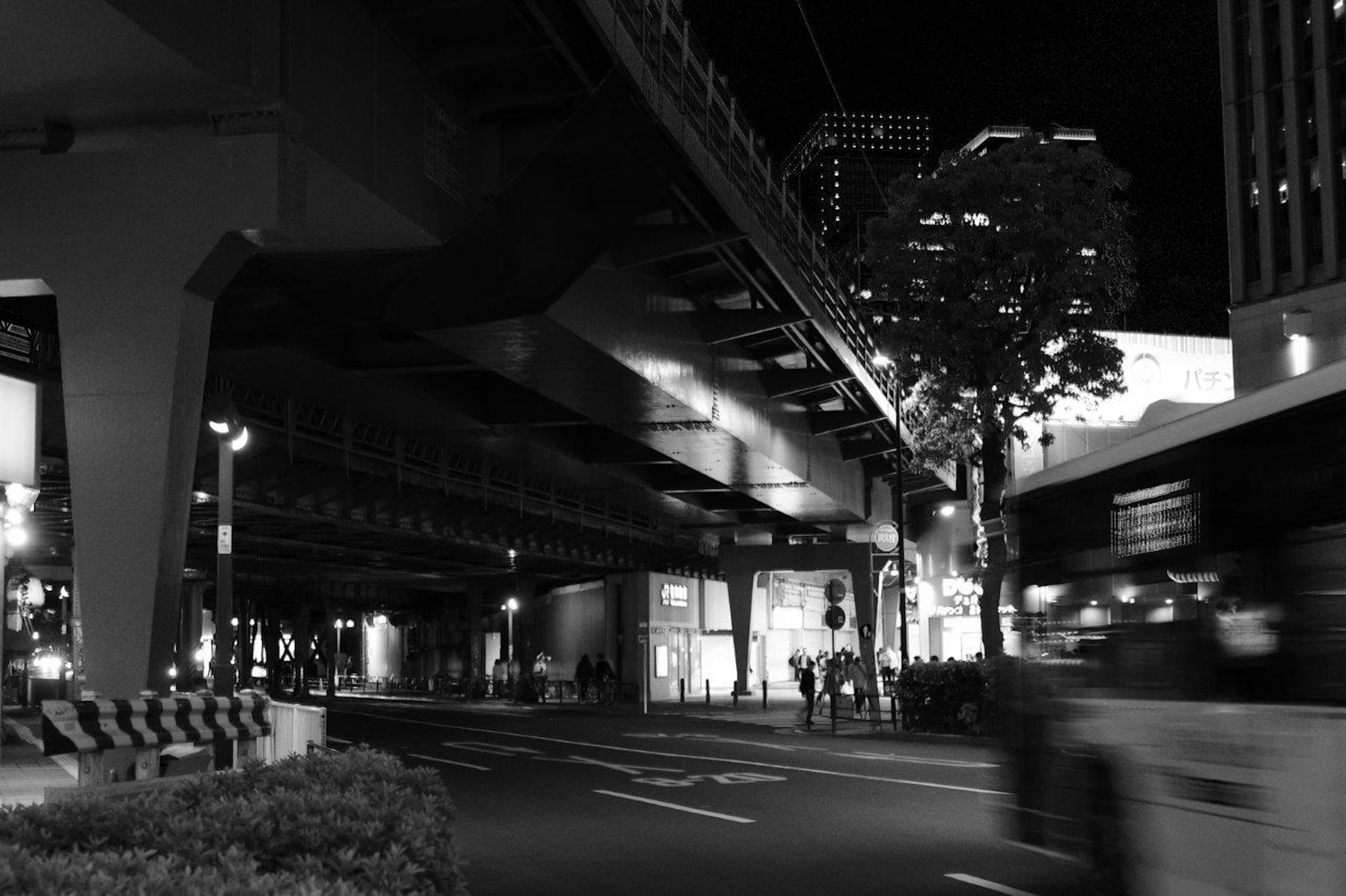 Paesaggio urbano notturno con pedoni sotto un'autostrada elevata