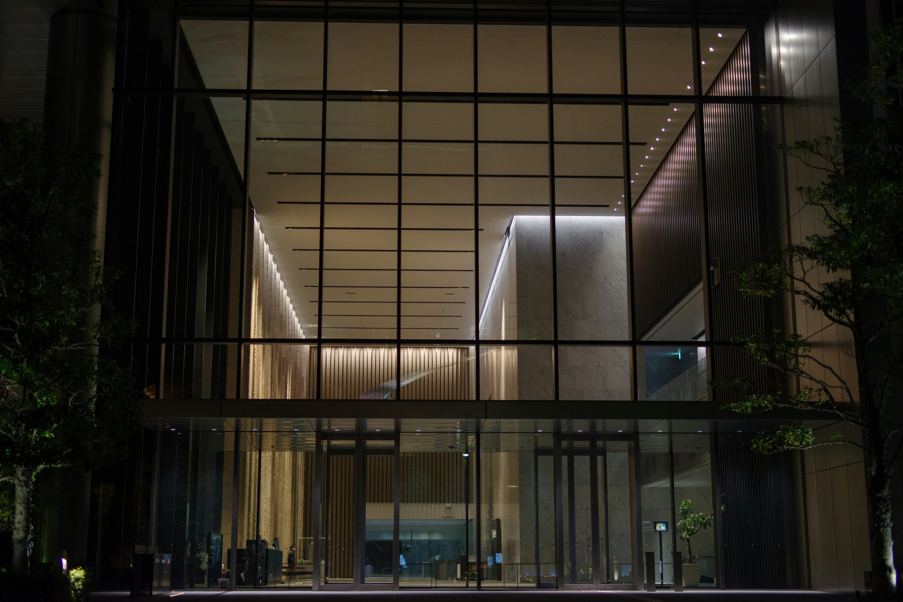 Edificio moderno de vidrio con entrada iluminada por la noche