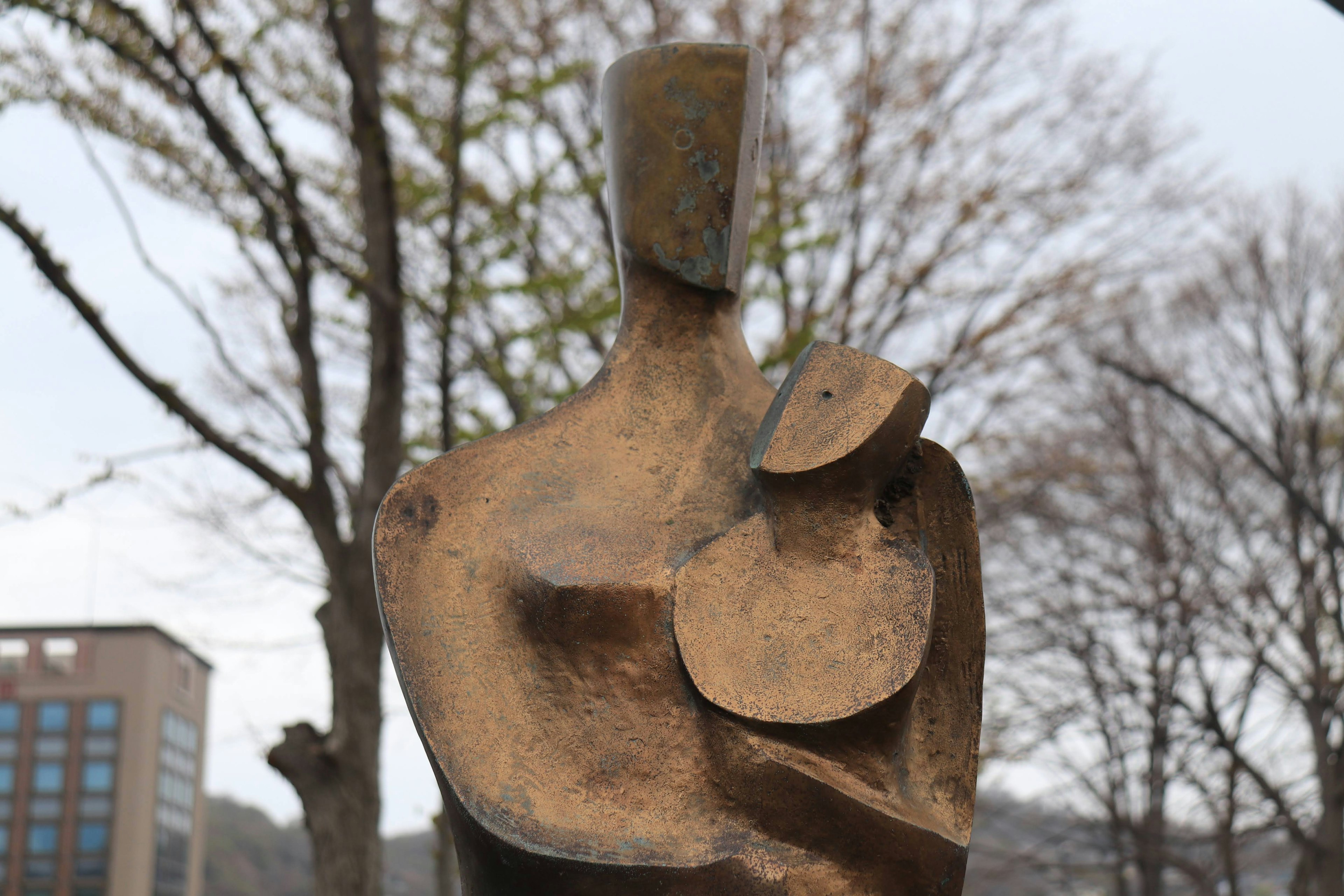 Escultura abstracta de una madre sosteniendo a un niño con una textura metálica