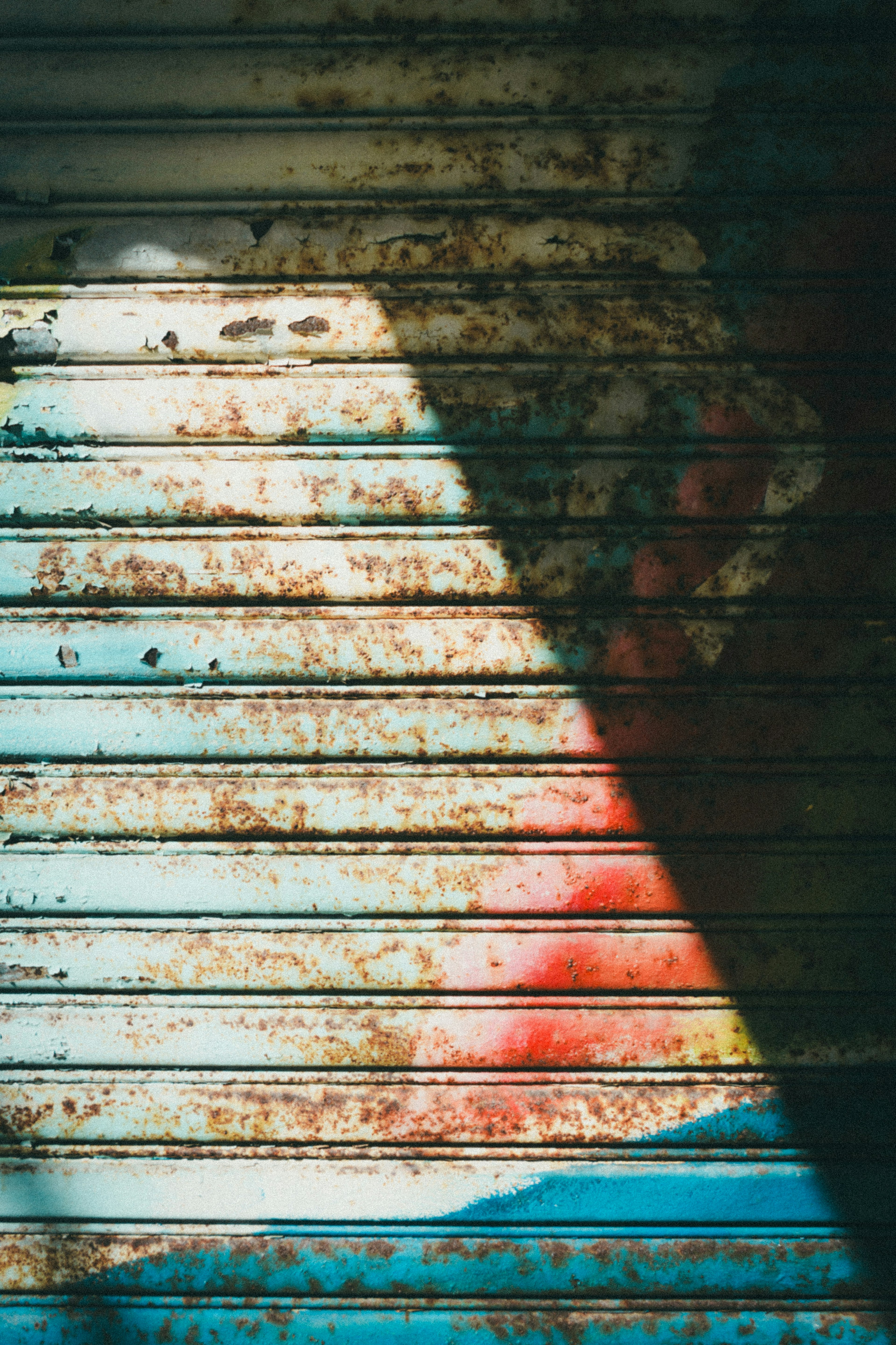 Colorful rusted metal seen through shutter slats