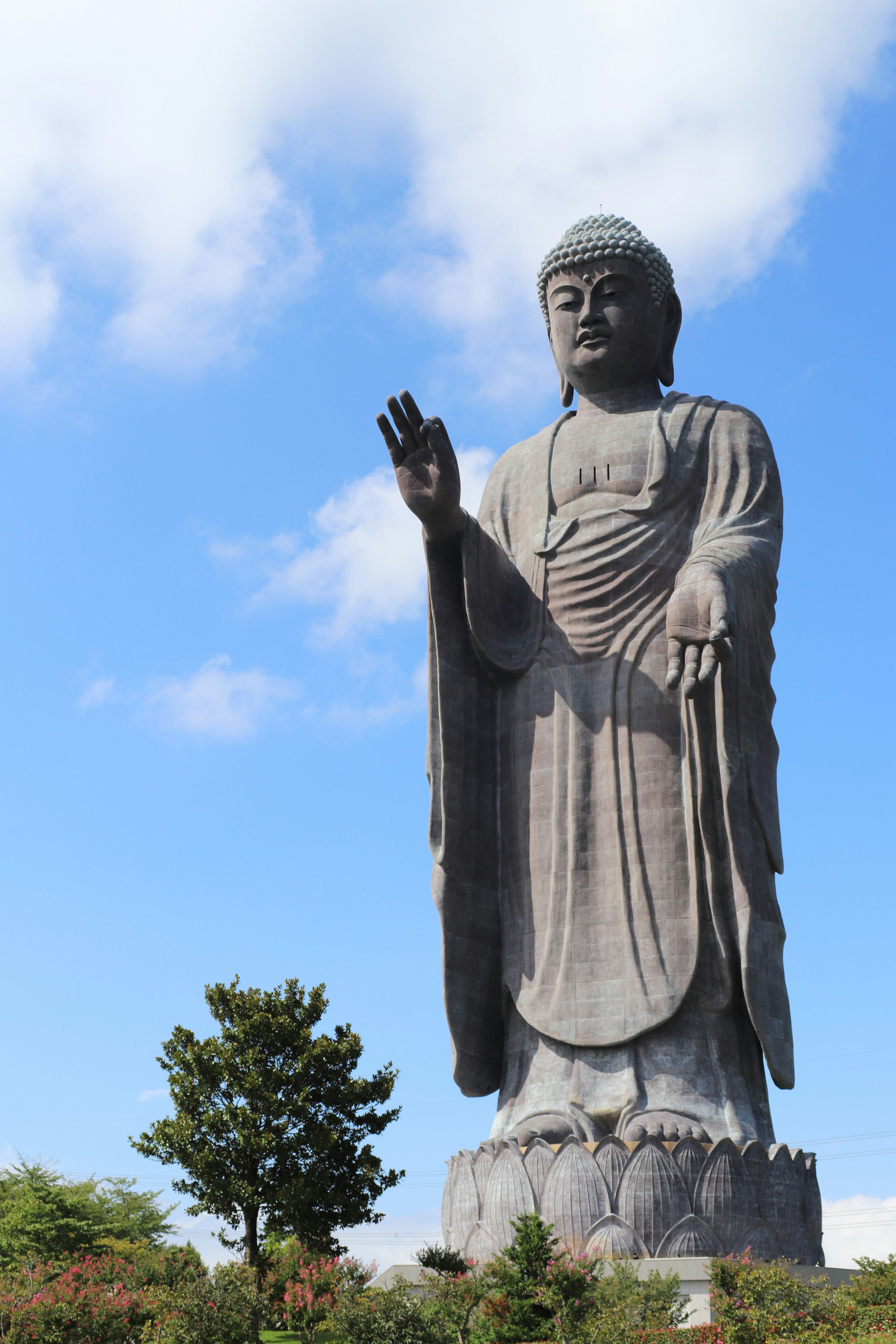 A towering statue of Buddha standing under a blue sky