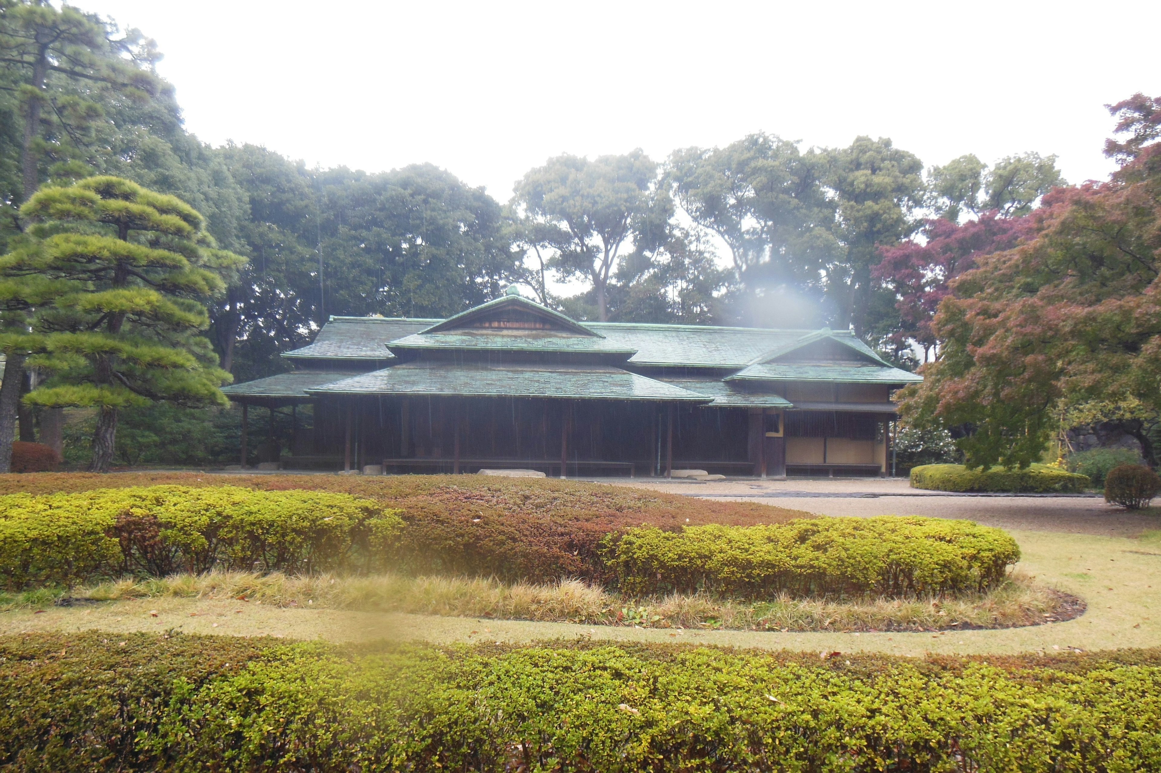 Rumah tradisional Jepang dengan atap hijau dikelilingi oleh vegetasi rimbun