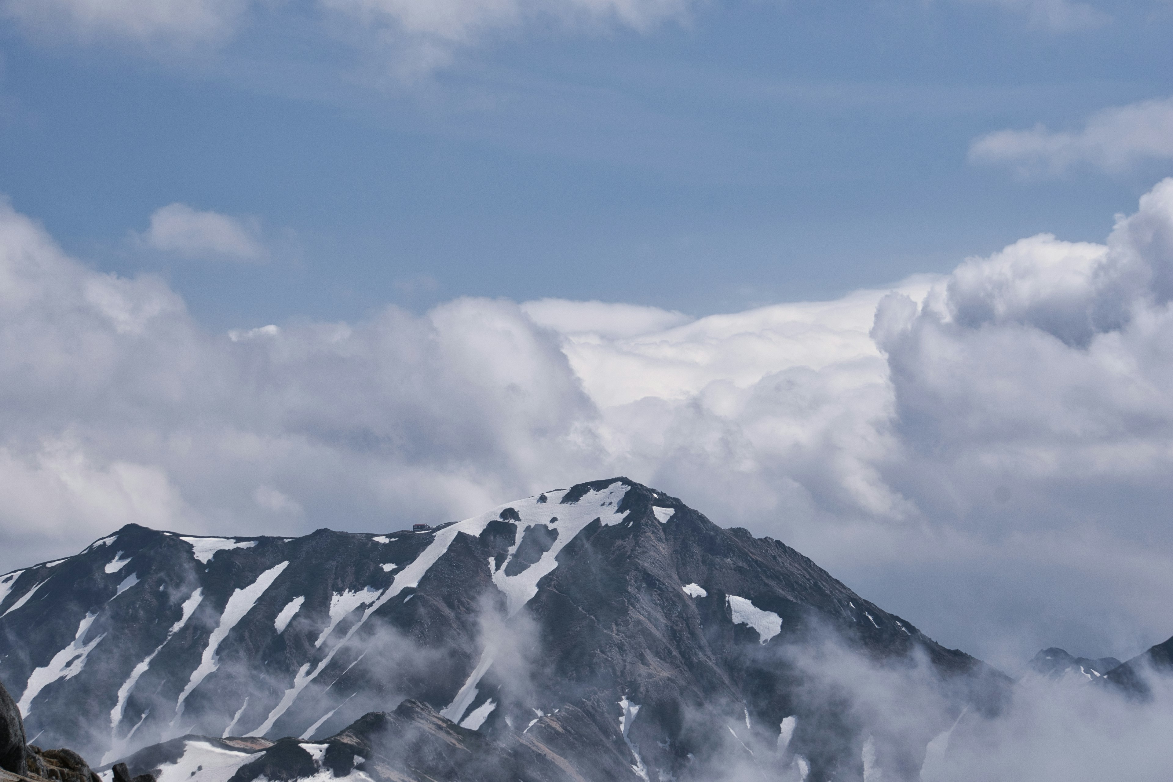 Verschneite Berge unter einem blauen Himmel mit Wolken