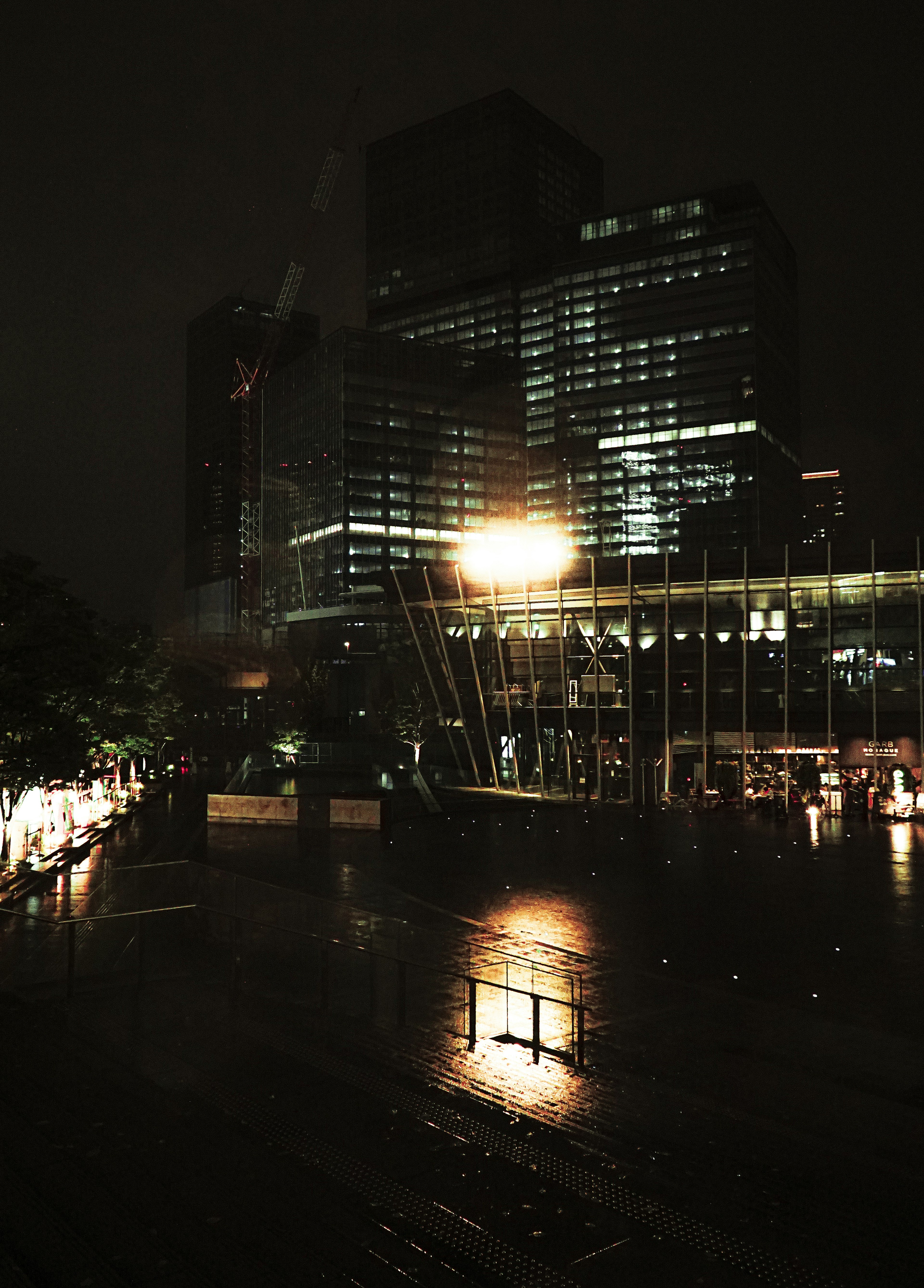 Night cityscape with reflections of high-rise buildings and lights on wet ground