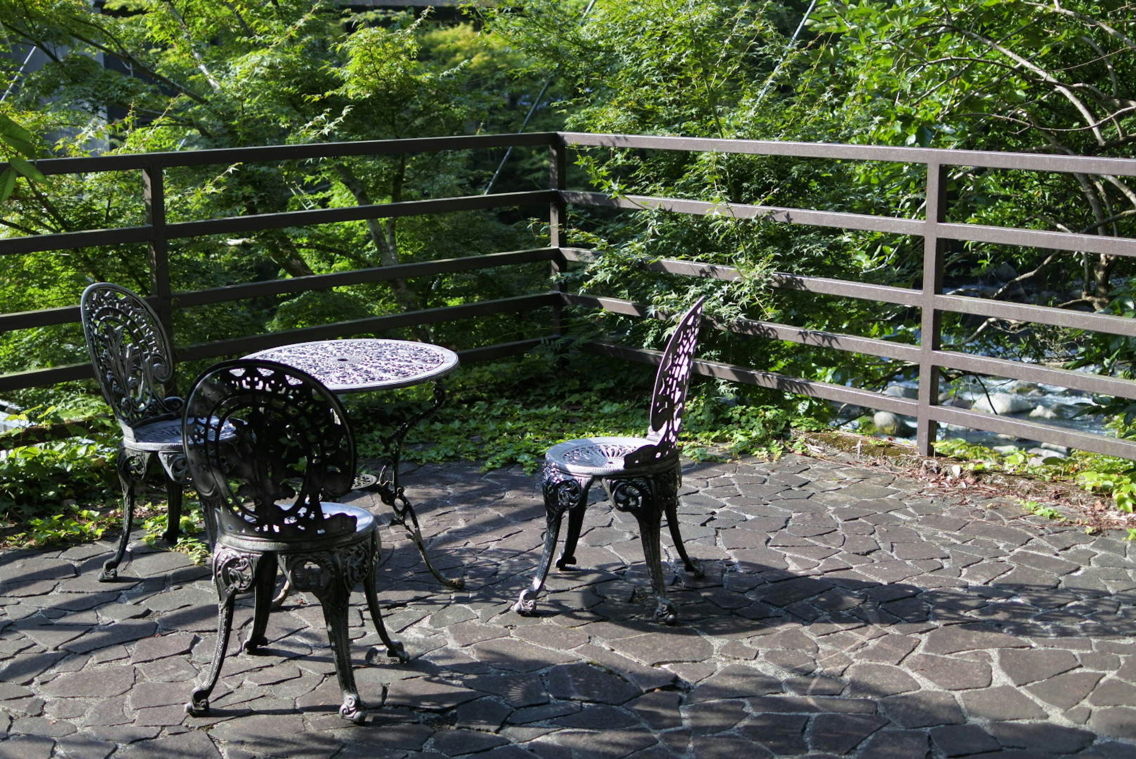 Conjunto de mesa y sillas de hierro en una terraza rodeada de vegetación