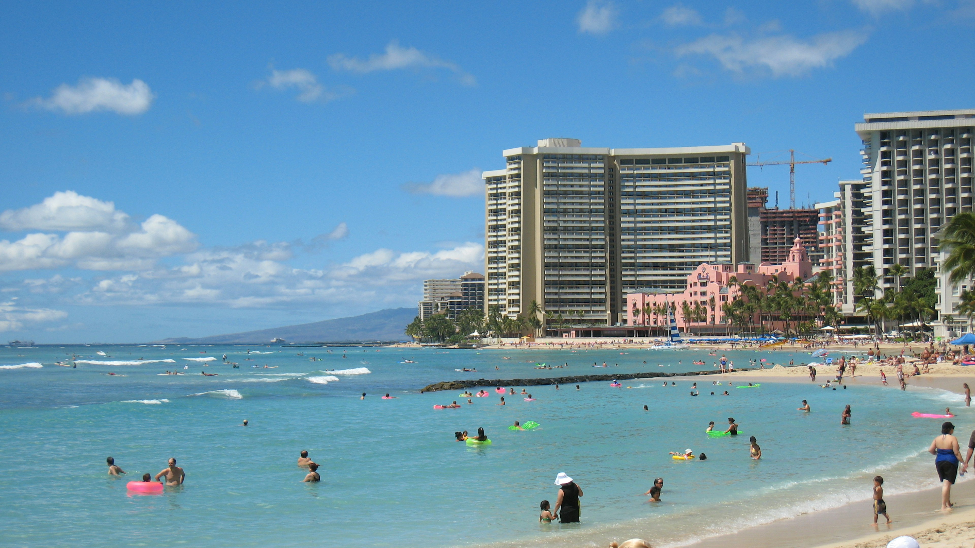 Pemandangan indah pantai Honolulu dengan orang-orang yang menikmati air biru jernih