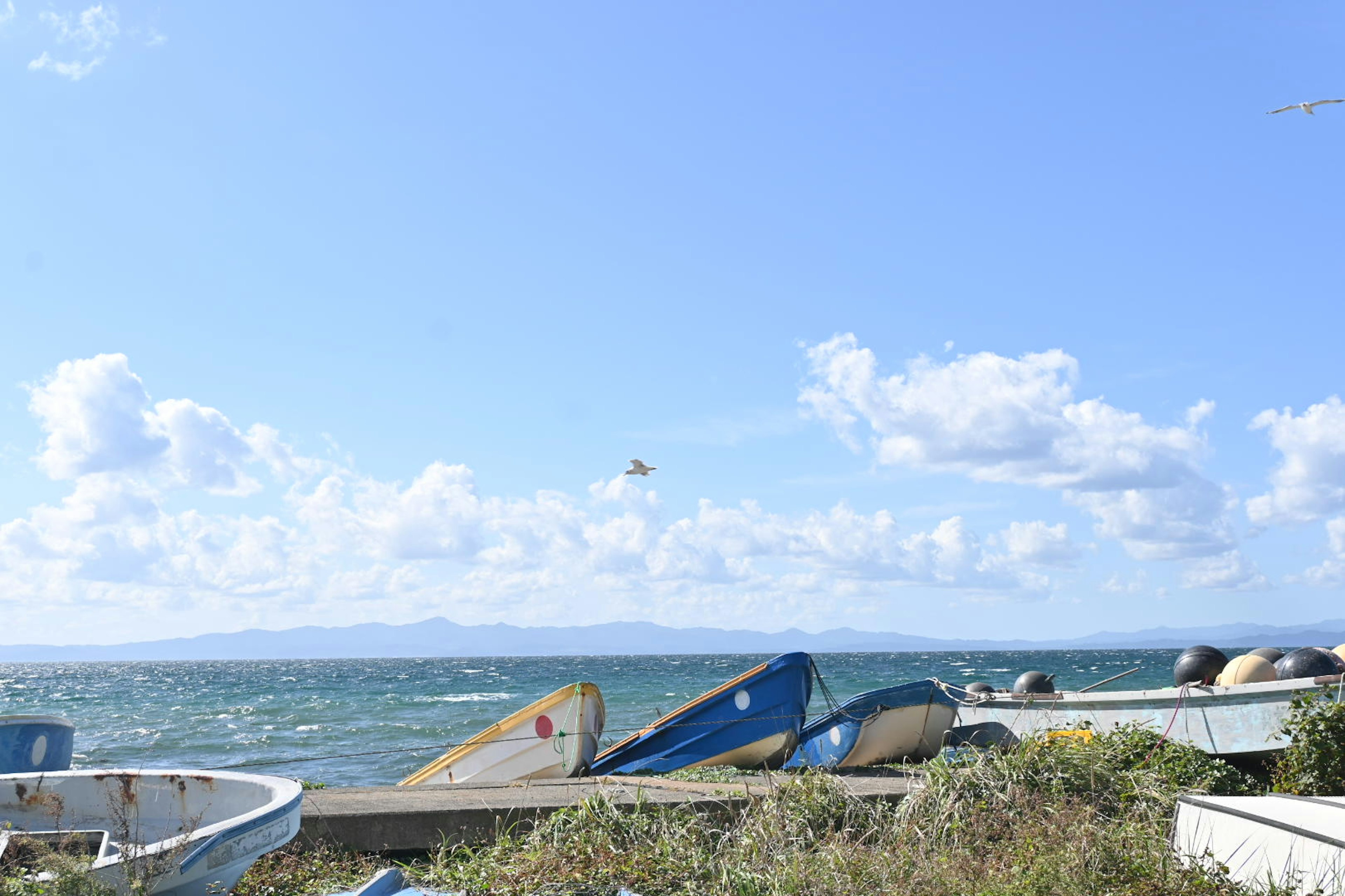 Vue pittoresque de petits bateaux au bord de la mer sous un ciel bleu avec des nuages