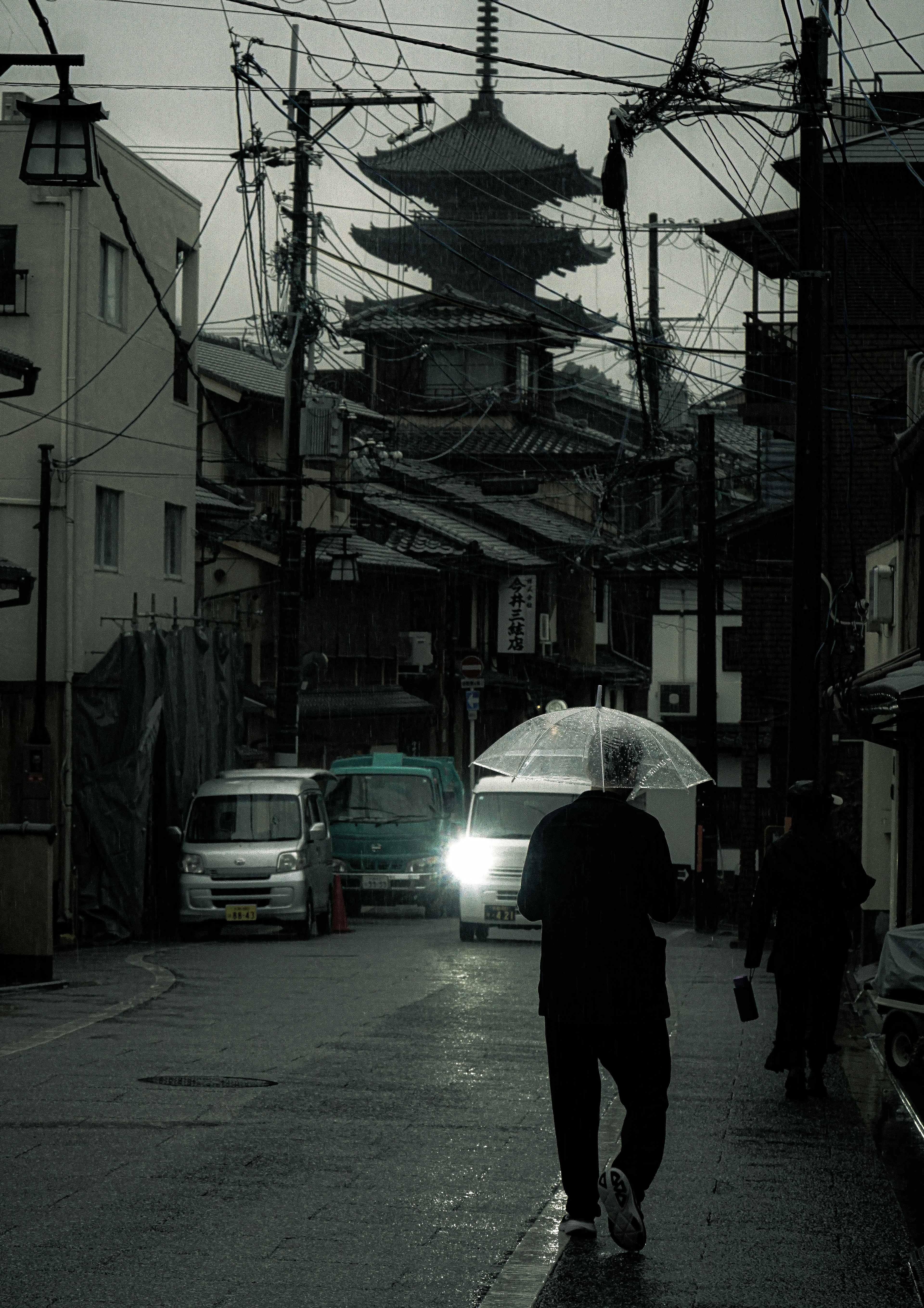 雨の中を歩く人と背景に見える五重塔の街並み