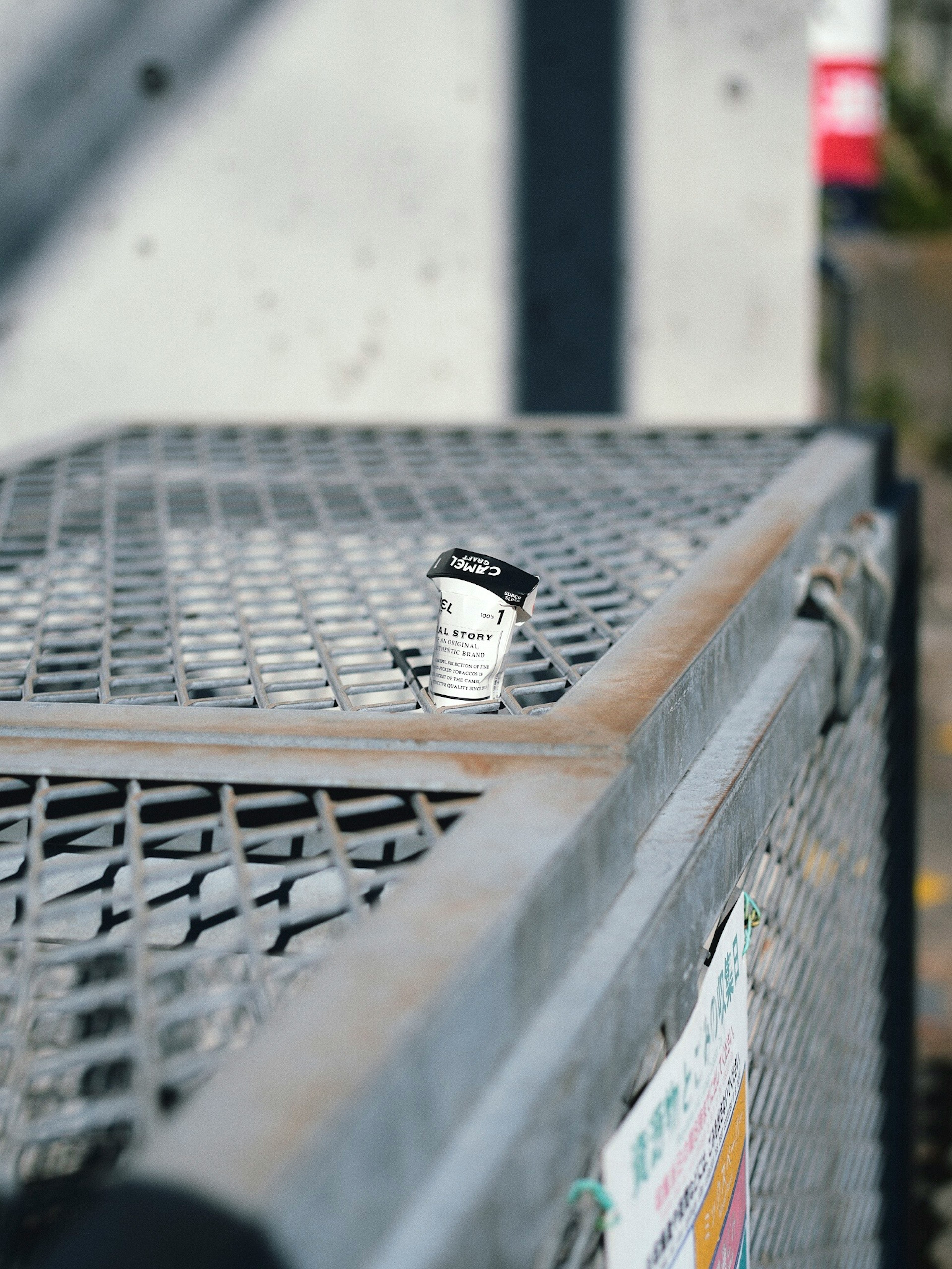 Image of a white cup standing on a metal mesh surface