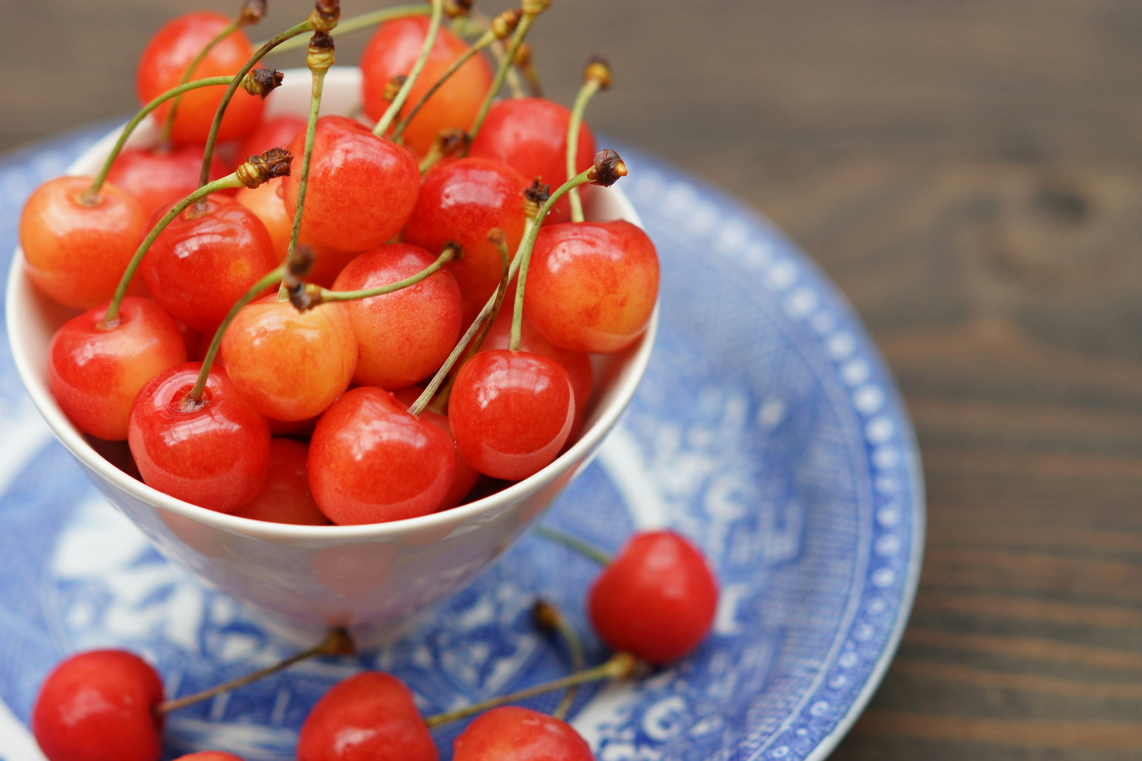 Red cherries in a white bowl on a blue plate