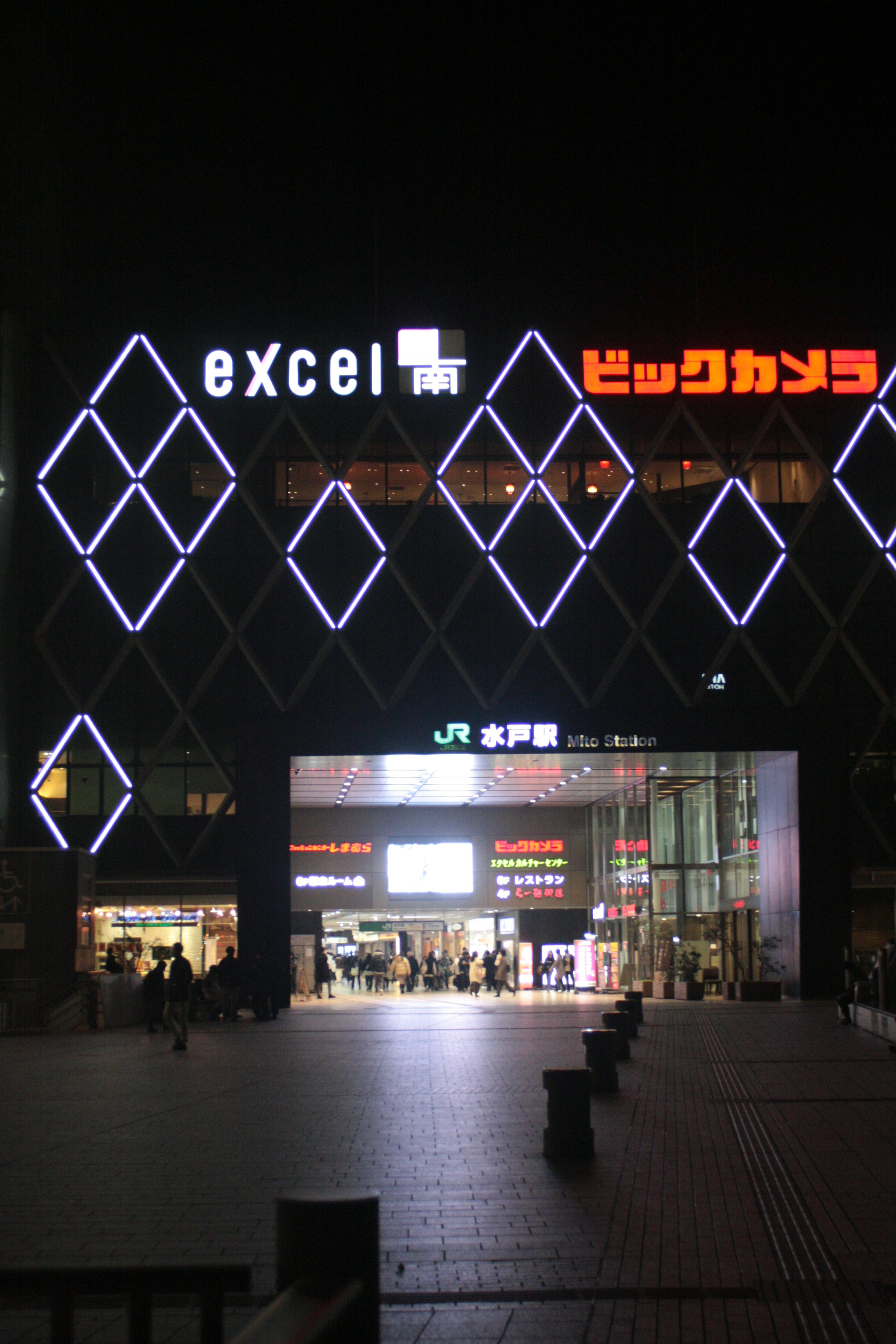 Vista esterna di un edificio commerciale con insegne illuminate di Bic Camera ed Excel di notte