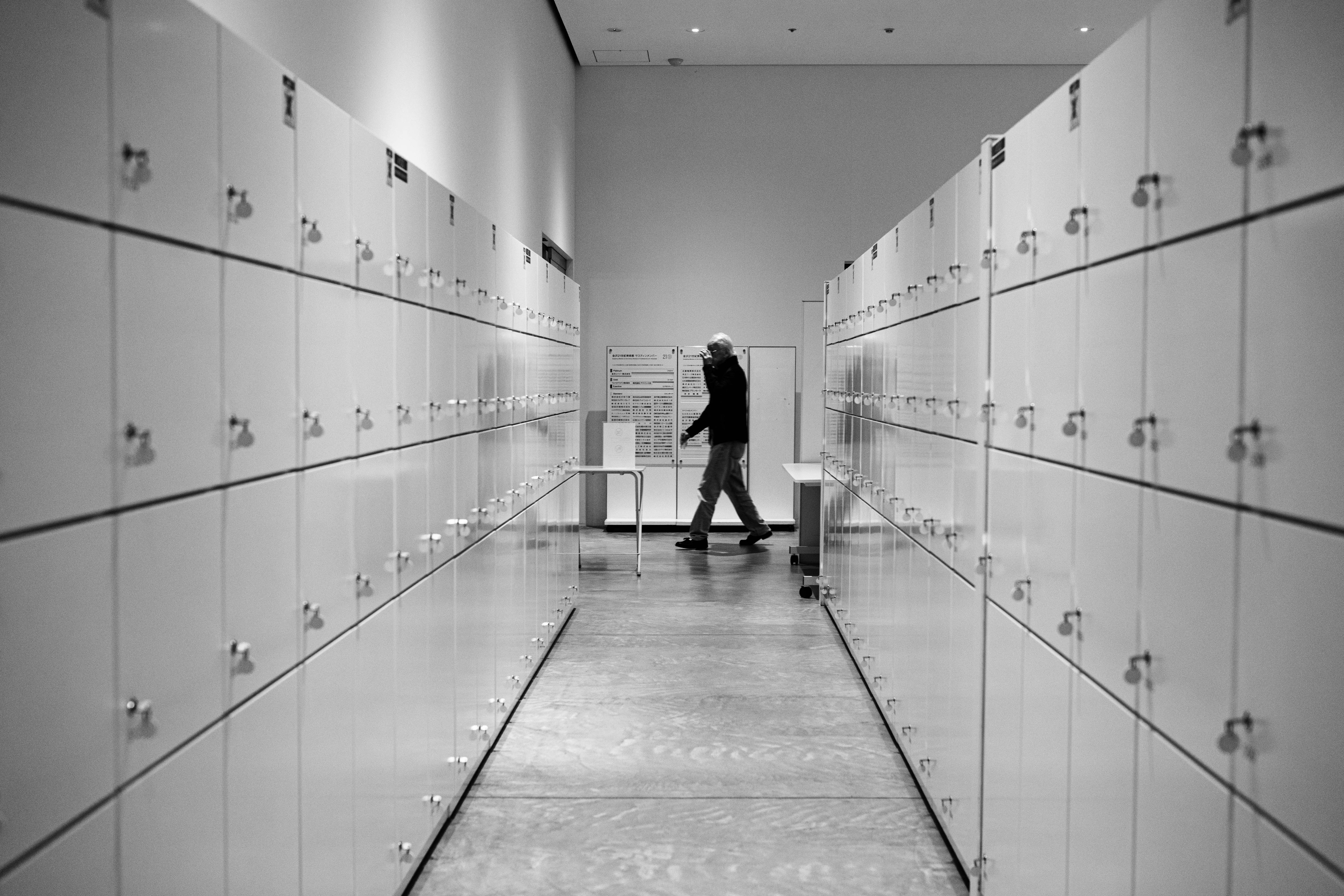 A space with neatly arranged black and white lockers and people walking