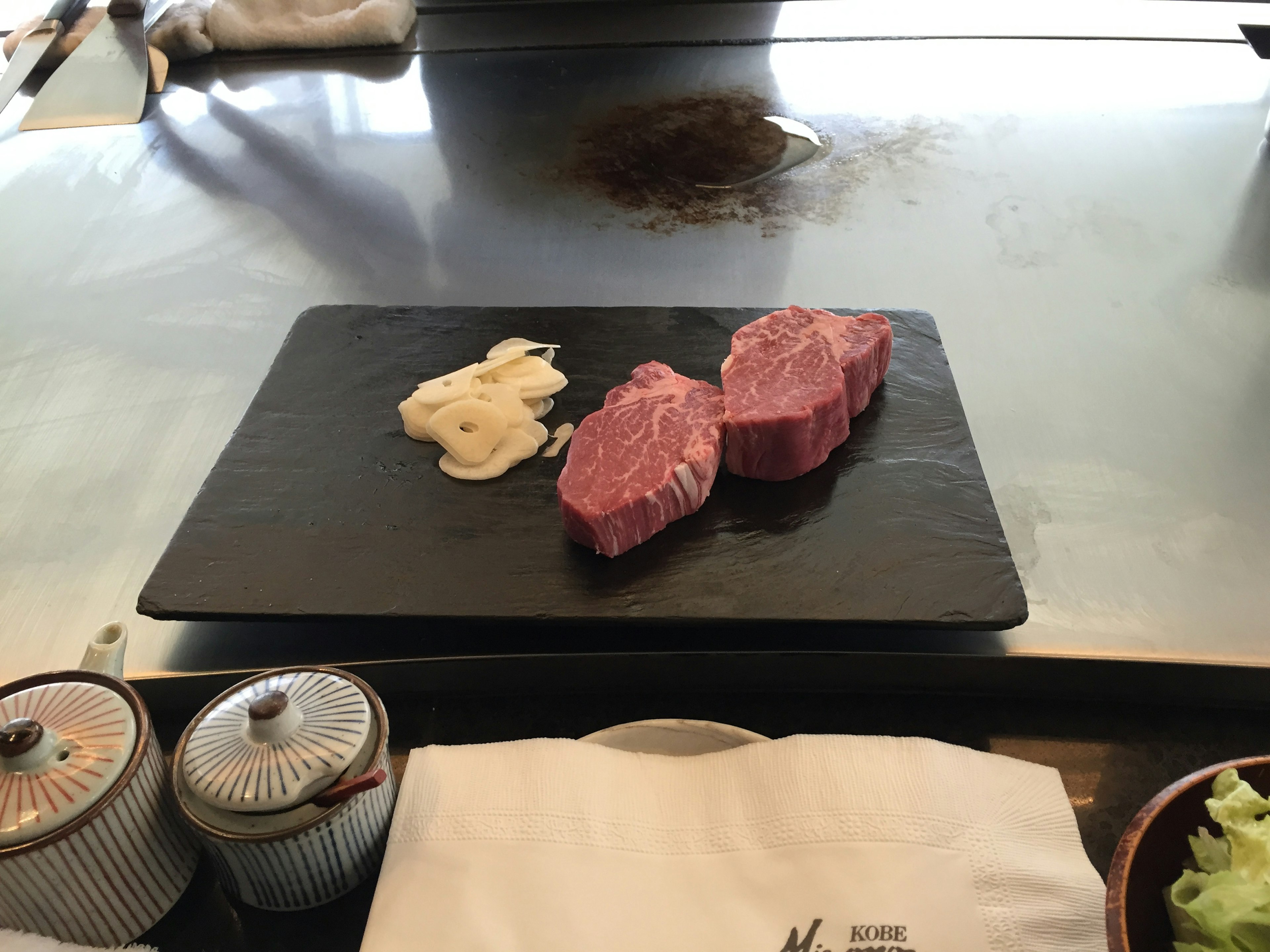 Trois morceaux de steak sur une assiette noire avec deux types de sauce