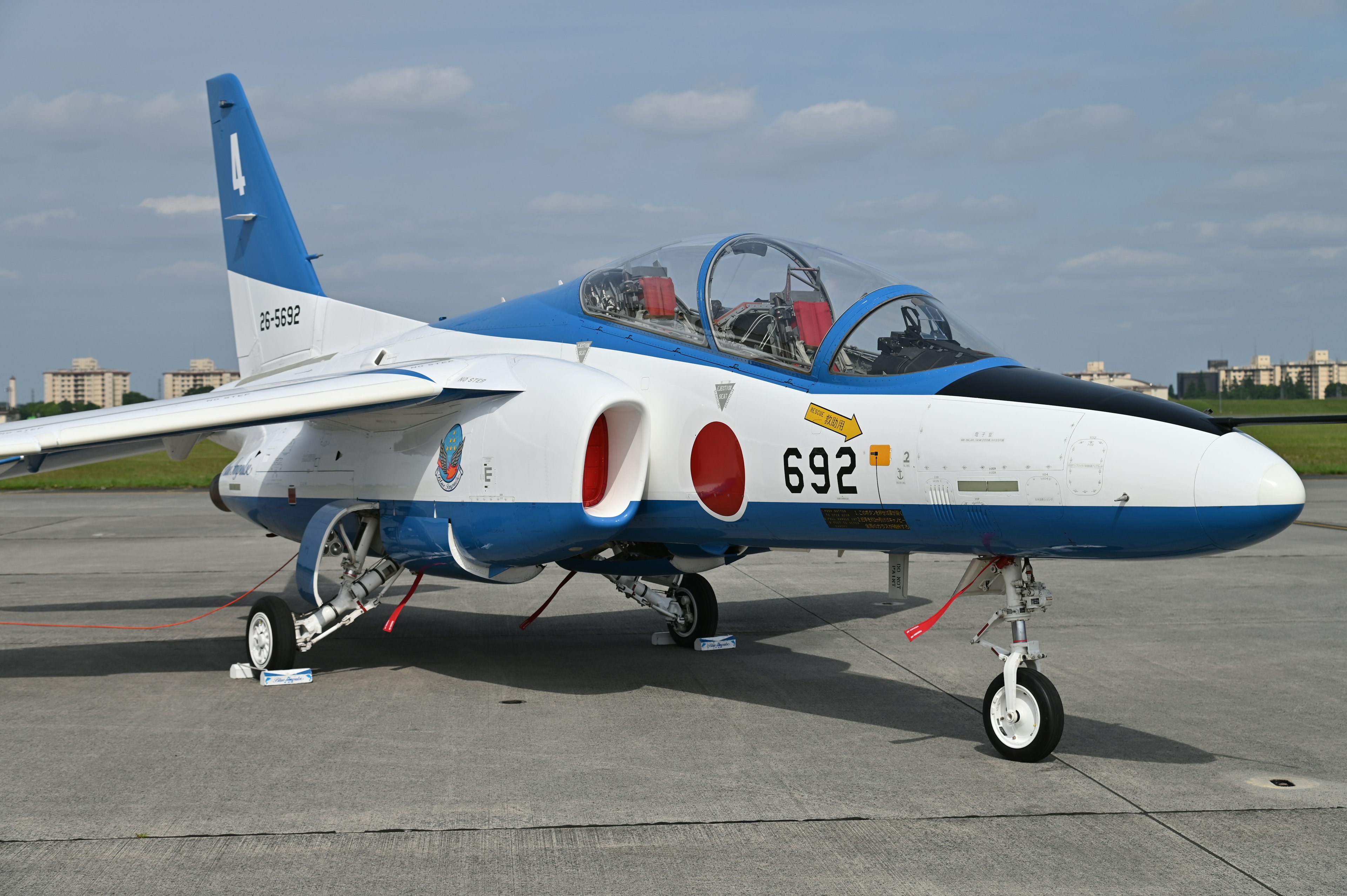 Un avión de entrenamiento japonés azul y blanco estacionado en la pista