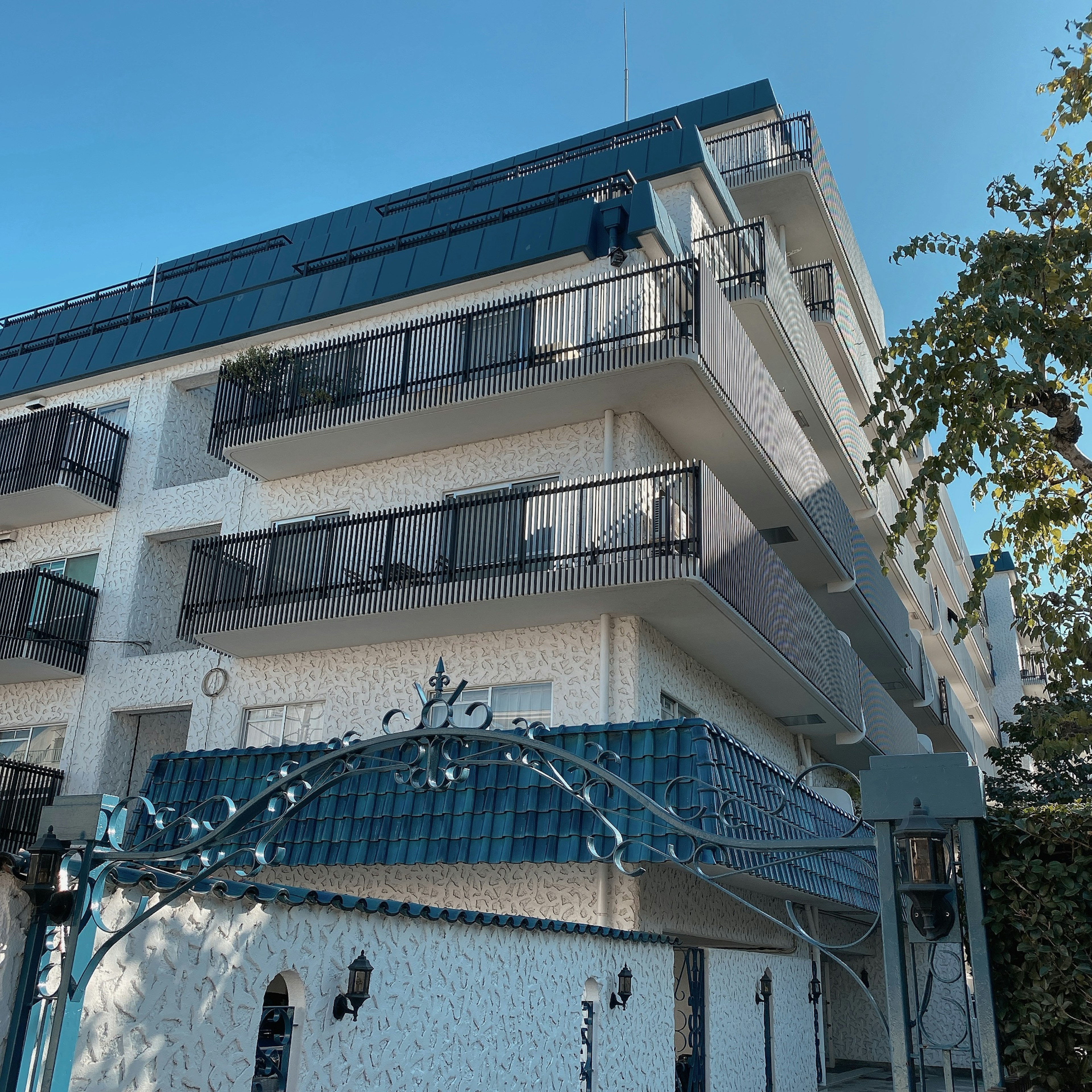 Three-story building with white exterior balconies and blue roof design