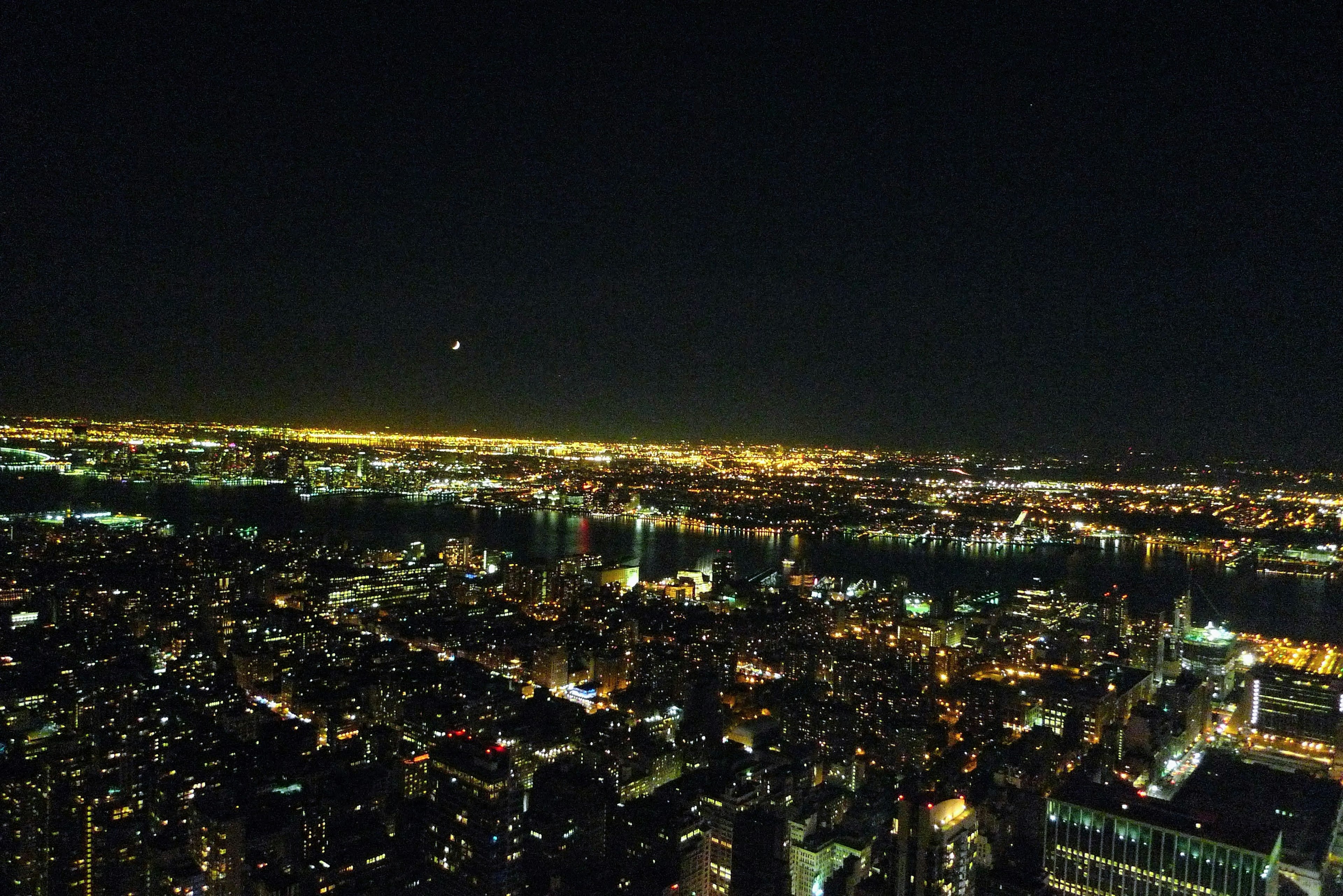 Aerial view of a cityscape at night with bright city lights and reflections on water