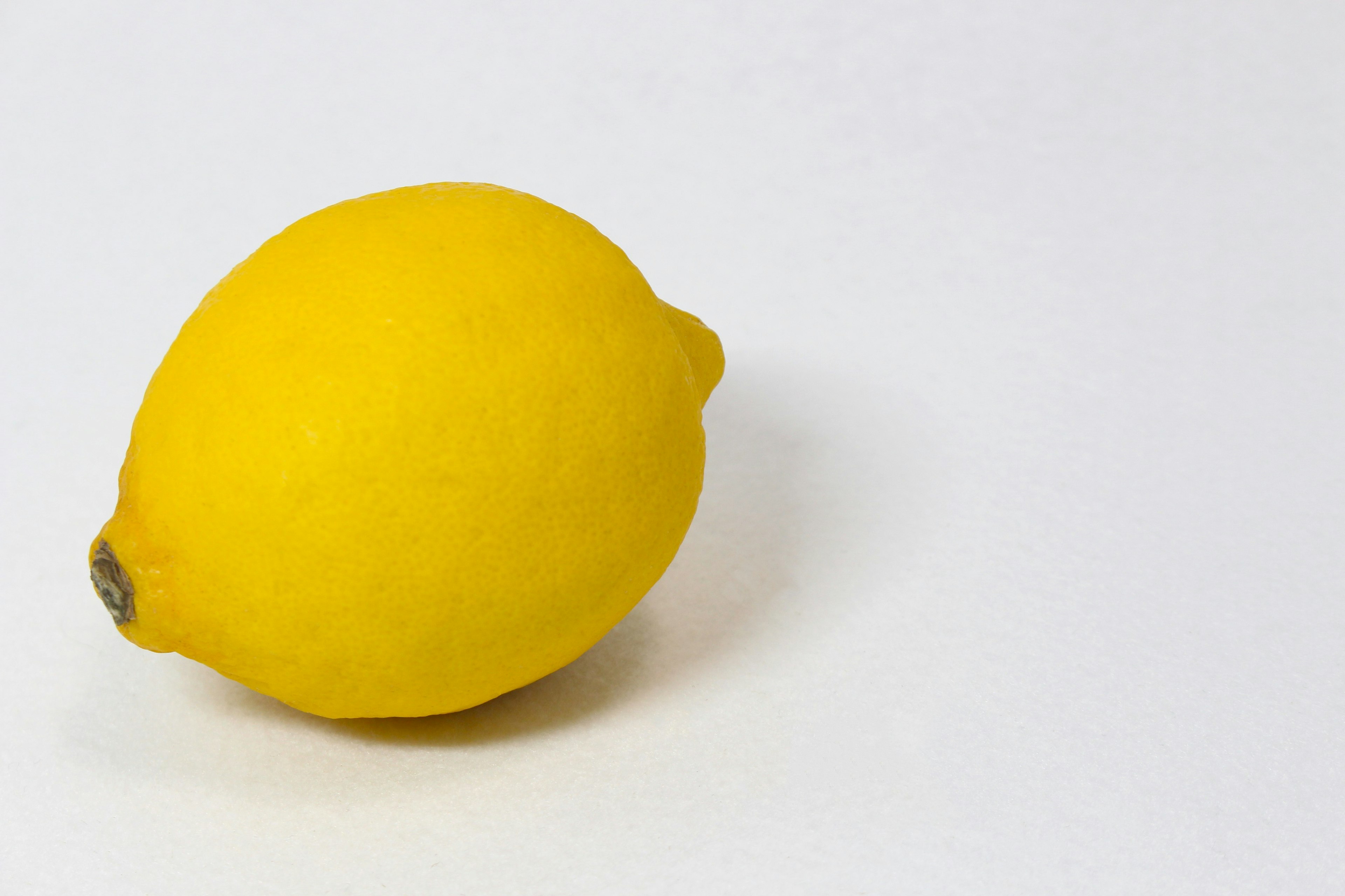 A bright yellow lemon placed on a white background