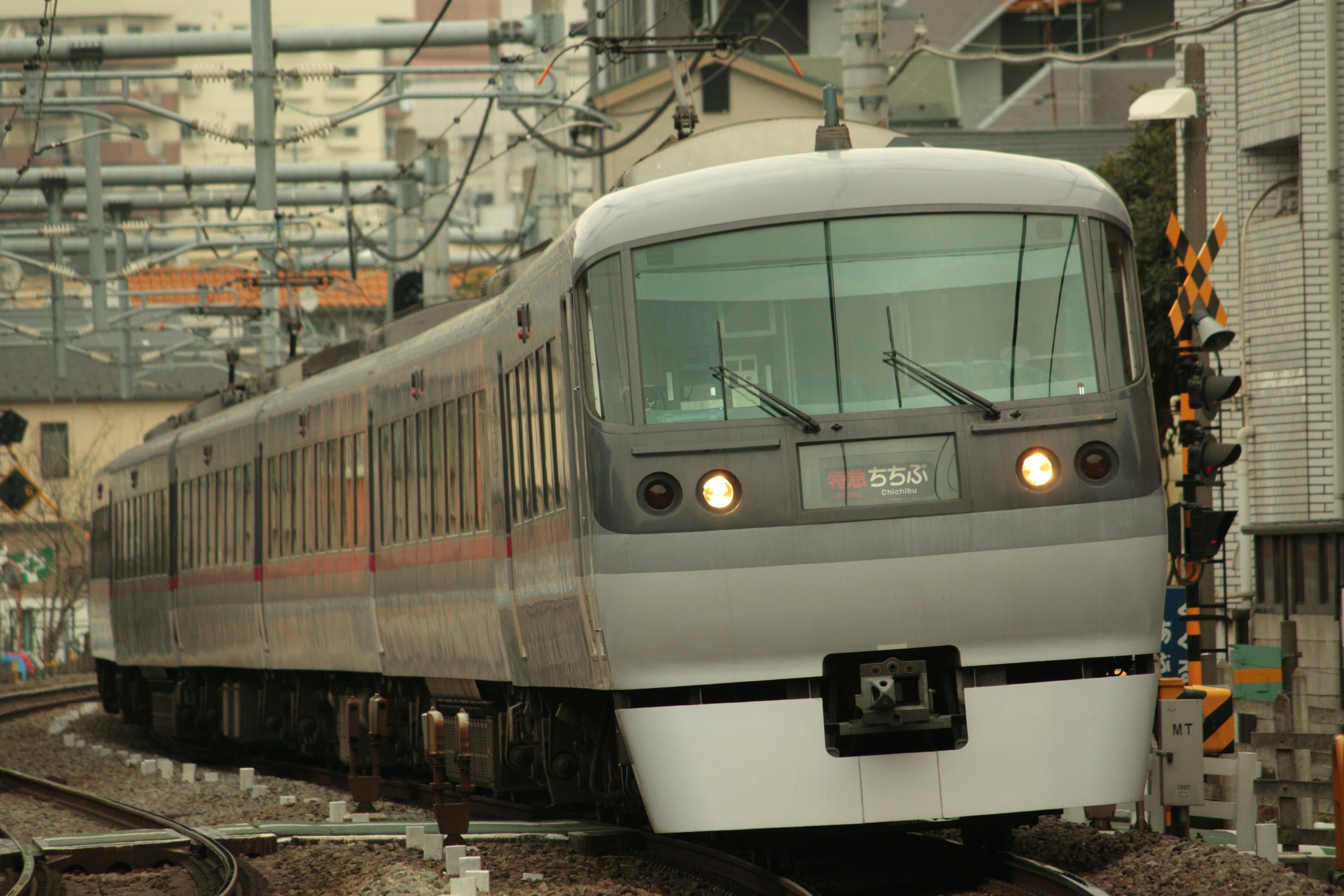 Silver train on railway with cityscape in background